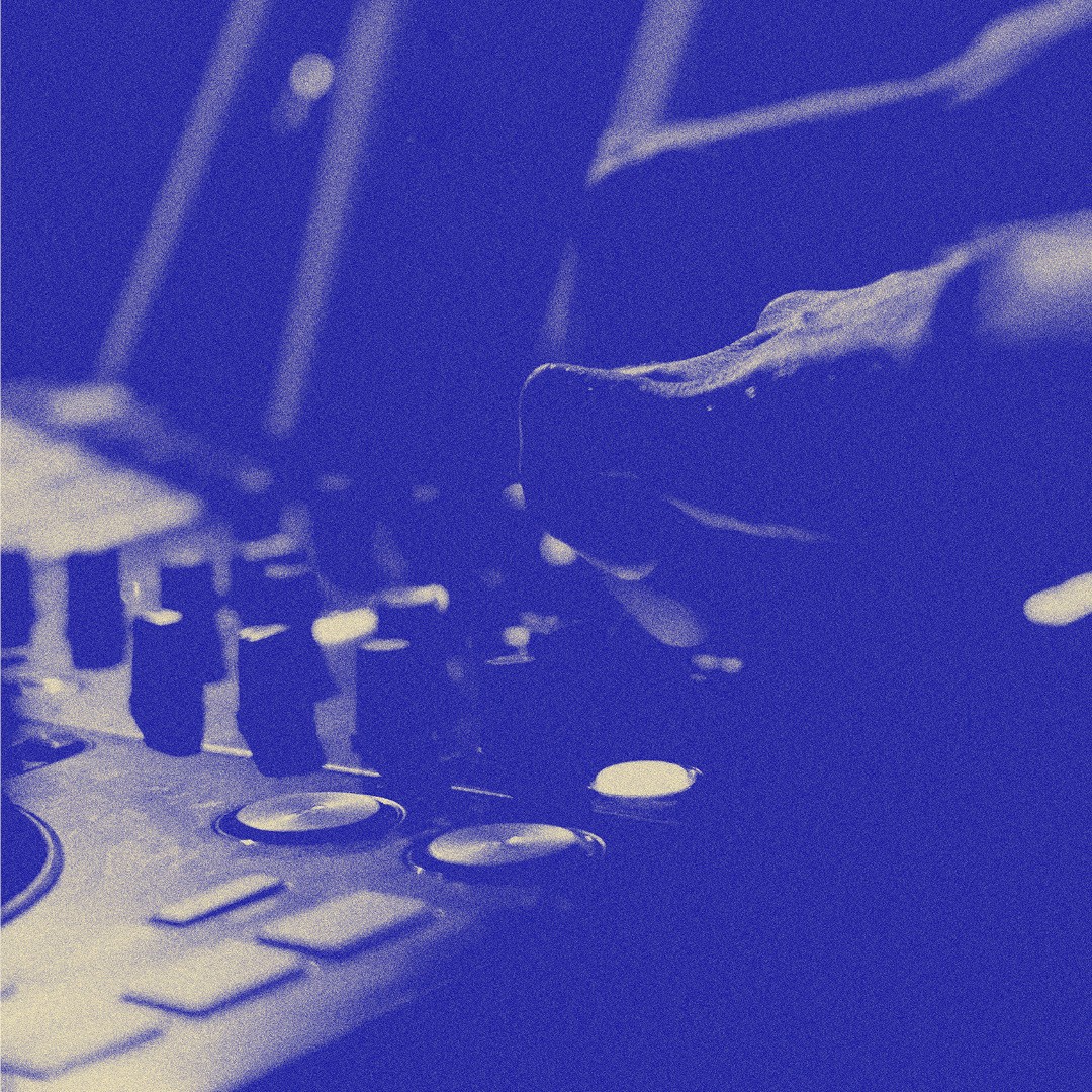 Nahaufnahme einer Hand, die einen DJ-Controller mit verschiedenen Reglern und Tasten in bläulichem Farbton bedient.