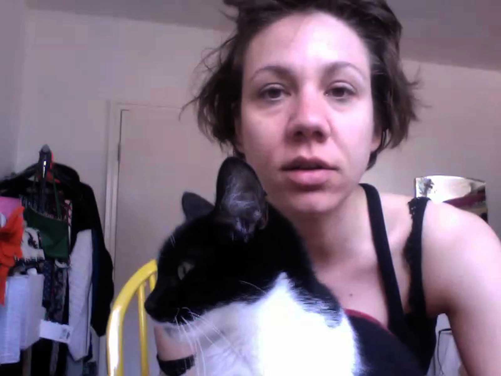 Eine ungekämmte Person sitzt neben einem schwarz-weißen Kater in einem hellen Raum.