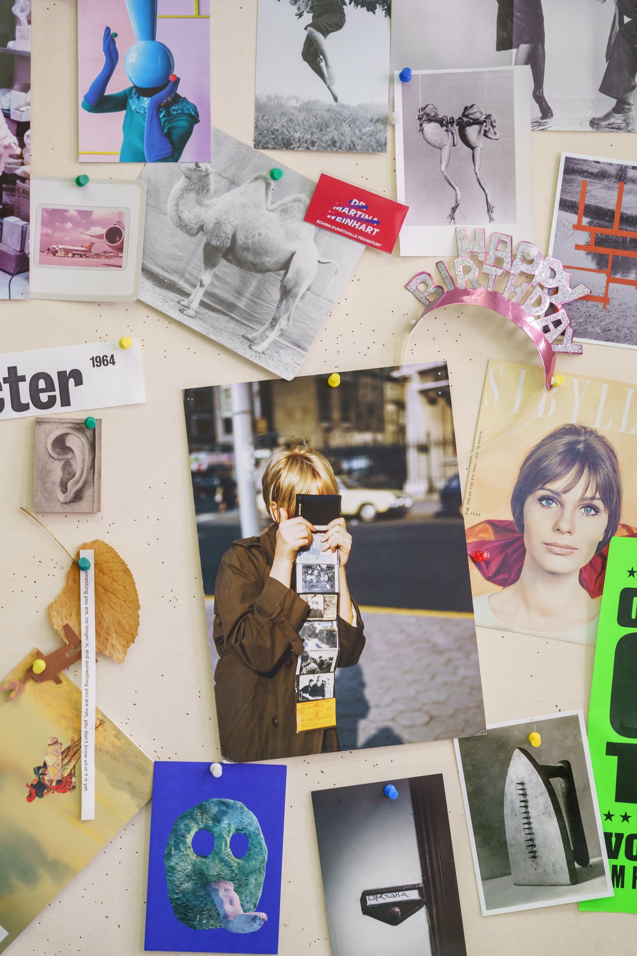 Collage aus Fotos, Postkarten und Erinnerungsstücken an einer Wand, mit Geburtstagsgrüßen und unterschiedlichen Motiven.
