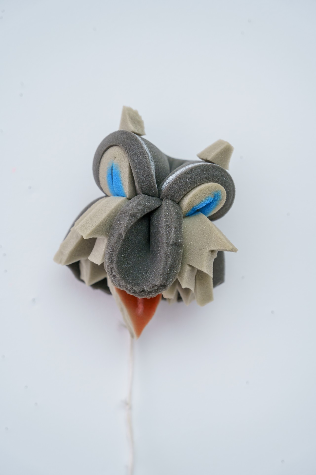 Kreative Skulptur eines Tierkopfes aus Schaumstoff in Grau und Blau, mit roter Zunge.