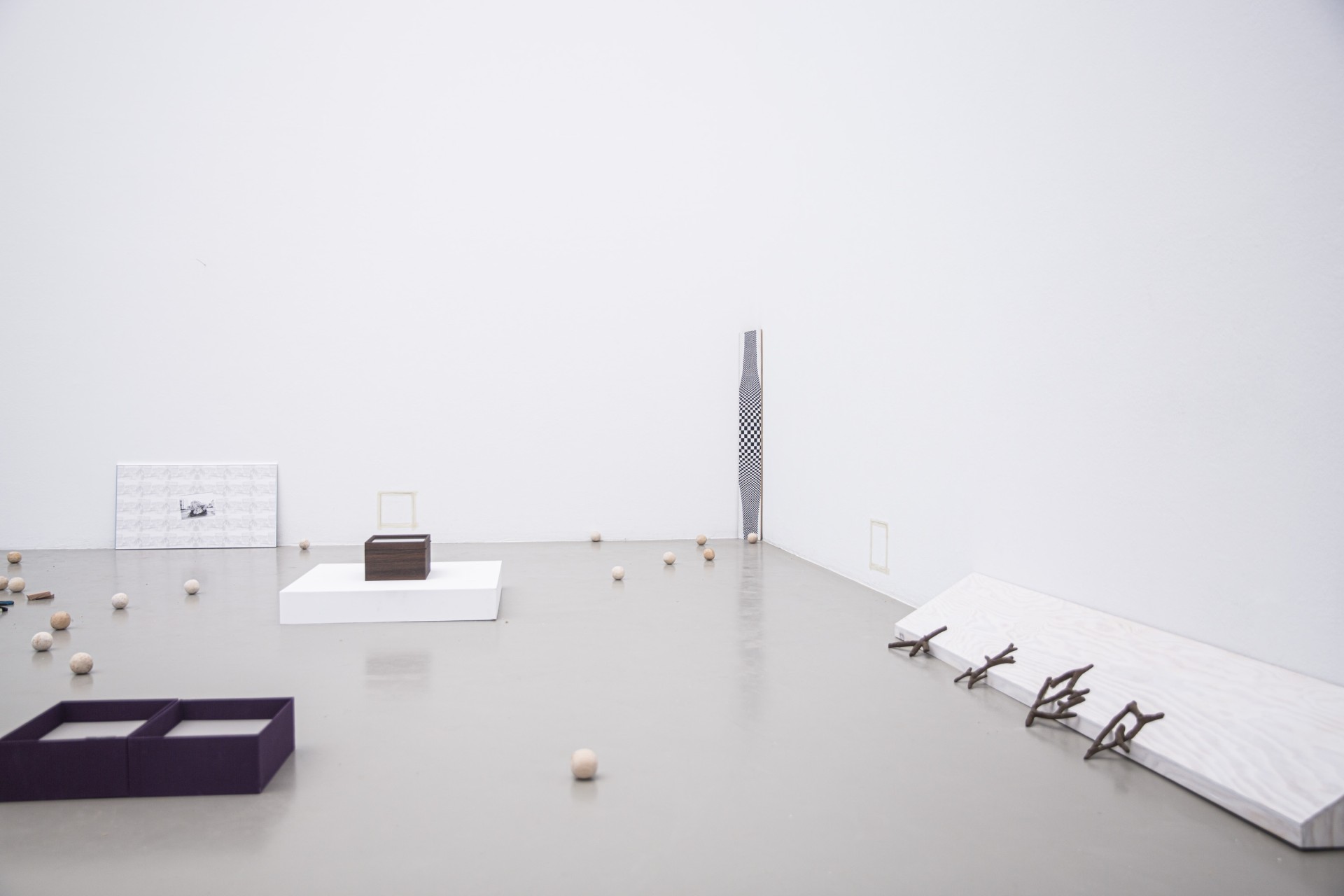 Minimalistische Kunstinstallation mit geometrischen Formen und natürlichen Materialien auf hellem Boden.