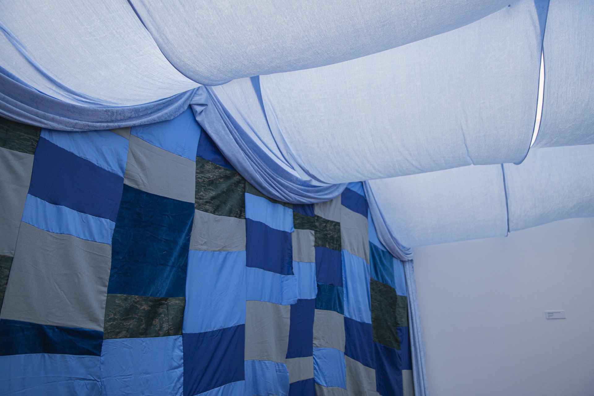 Raum mit blauem Wandteppich und drapiertem Stoff, der den Innenraum schmückt.