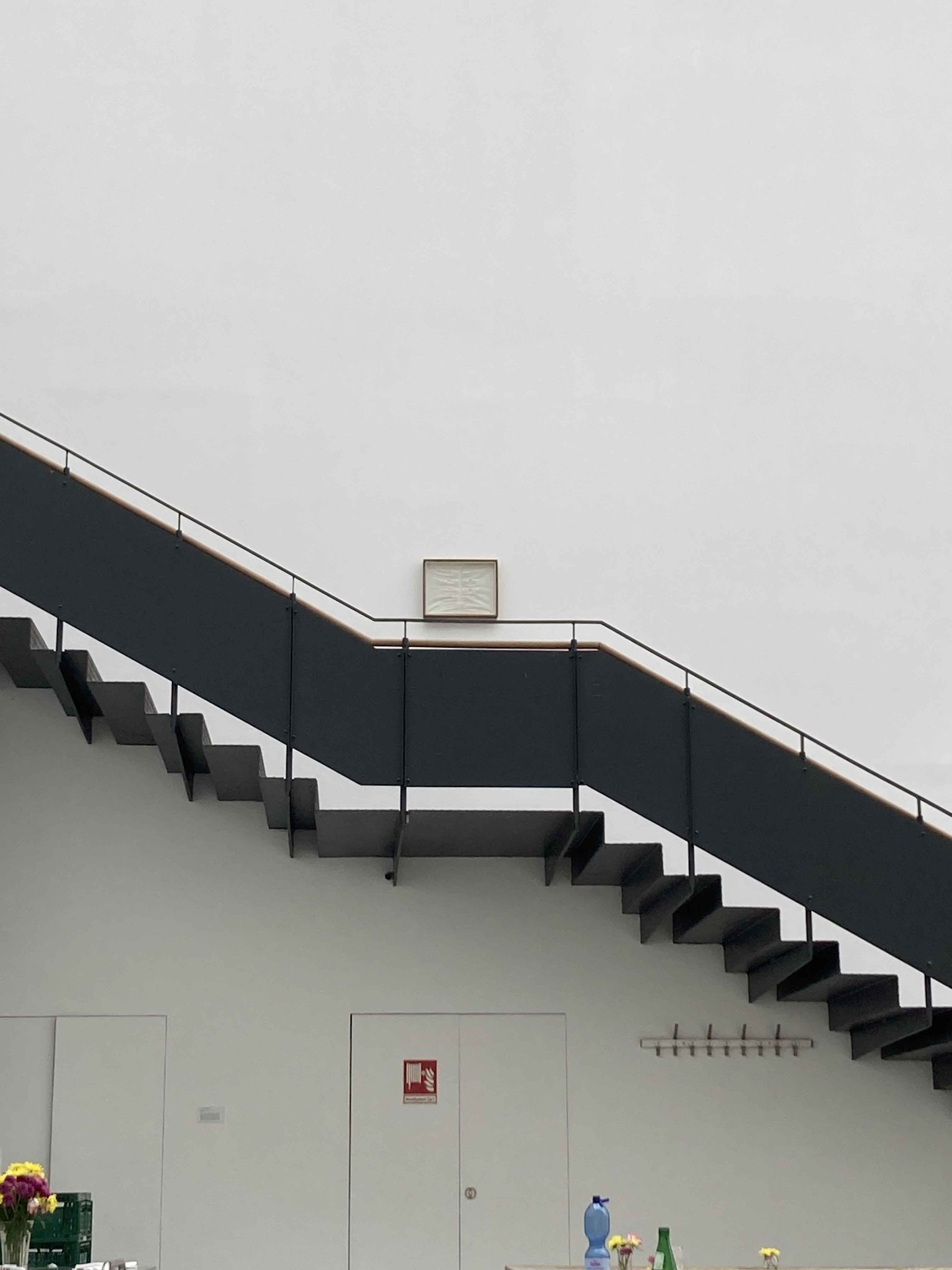 Moderner Raum mit schlichter Treppe zu einem Wandbild; klare Linien und minimalistische Ästhetik.