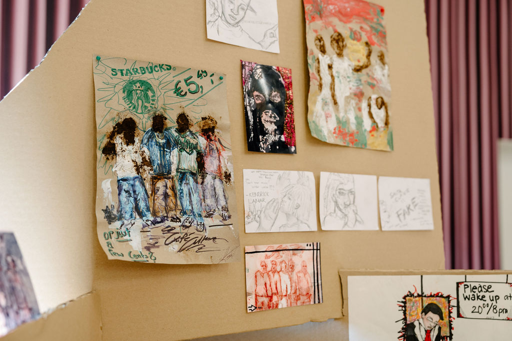 Kunstwerke aus verschiedenen Medien an einer Wand, darunter Skizzen und bunte Illustrationen.