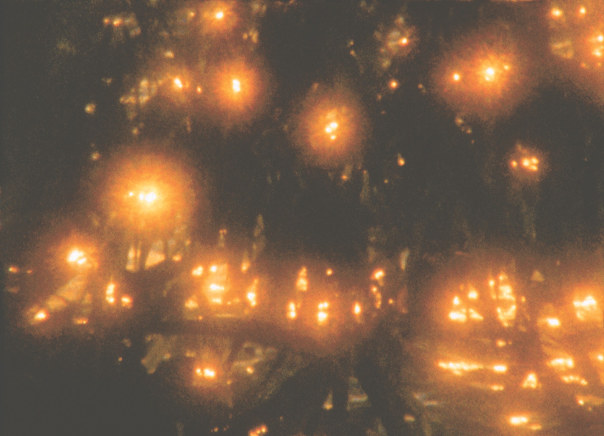 Lichtpunkte strahlen in einem dunklen, unscharfen Hintergrund und schaffen eine stimmungsvolle, geheimnisvolle Atmosphäre.