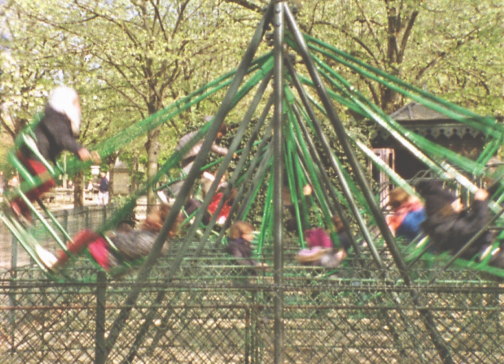 Kinder schwingen fröhlich auf einer grünen Schaukel im Park, umgeben von Bäumen und einer schönen Atmosphäre.