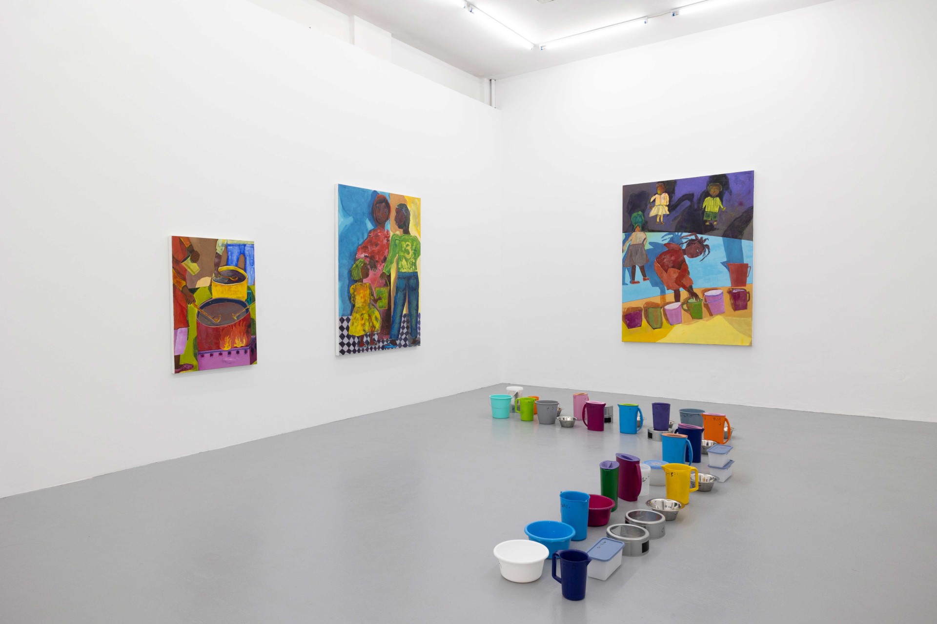 Modern gallery with colorful paintings on the walls and a row of colorful buckets and containers on the floor.