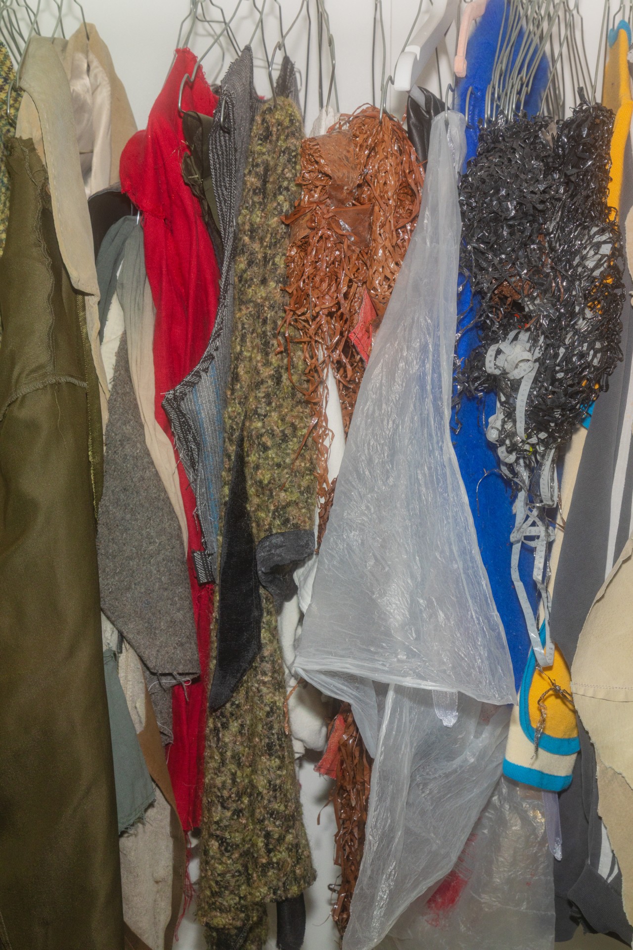 Bunt gemischte Kleidungsstücke hängen eng an Drahtkleiderbügeln.