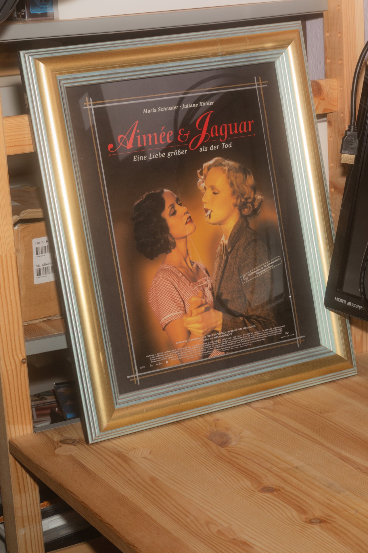 Filmplakat "Aimée & Jaguar" in goldenem Rahmen, zeigt die emotionale Verbindung zweier Frauen.