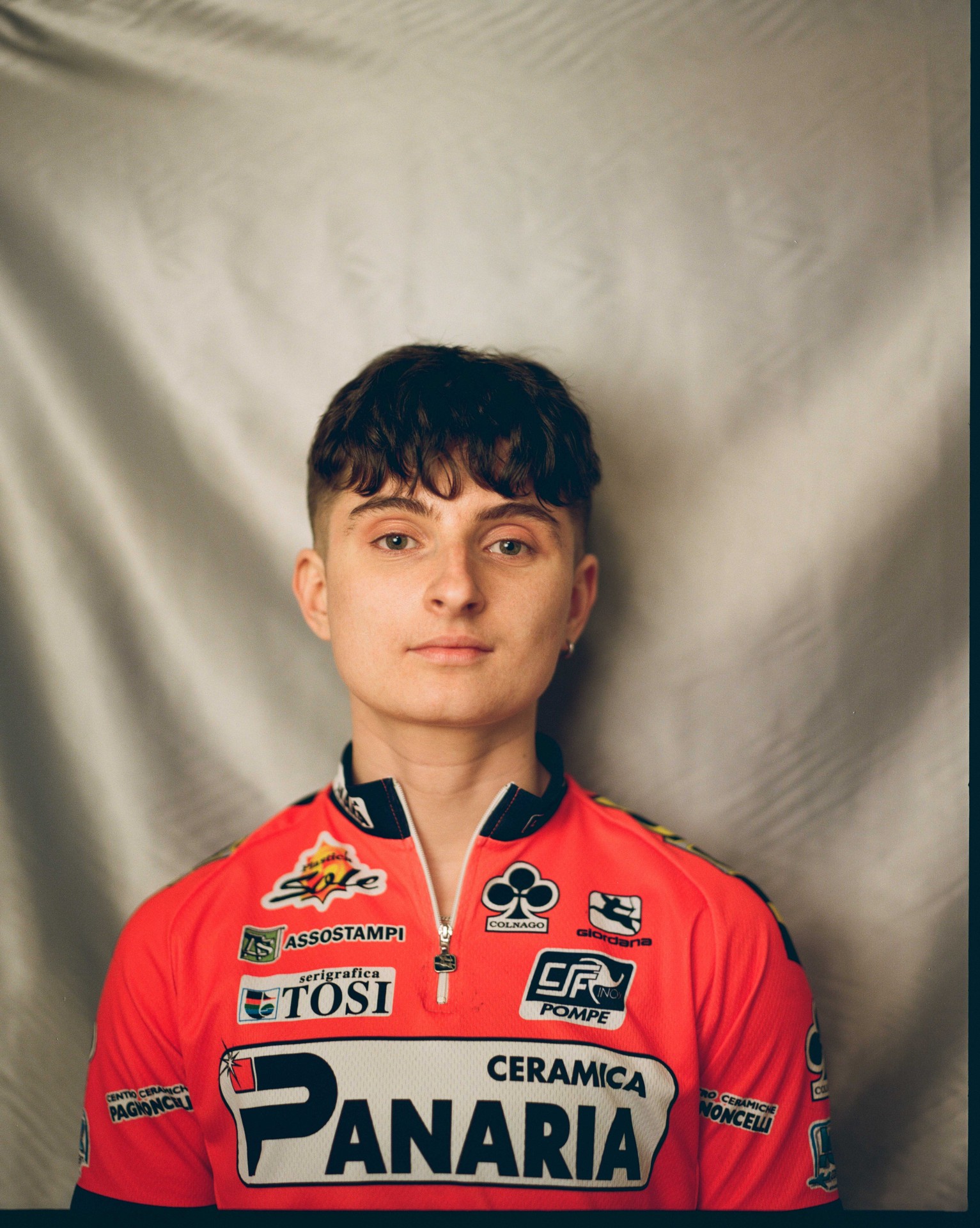 Porträt einer Person in rotem Radsporttrikot vor neutralem, hellem Hintergrund.
