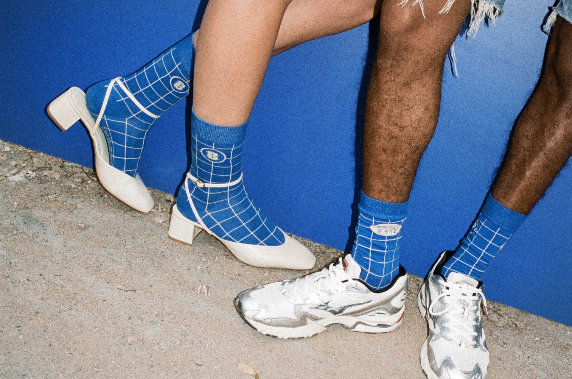 Modische Schuhe: weiße Pumps und silberne Sneakers, kombiniert mit grafischen blauen Socken.