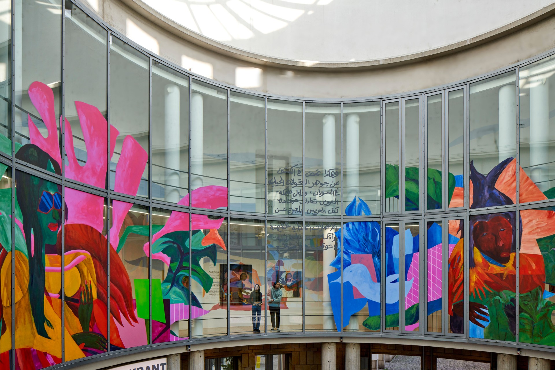 Colorful mural in a modern room with glass walls and people in the foreground.