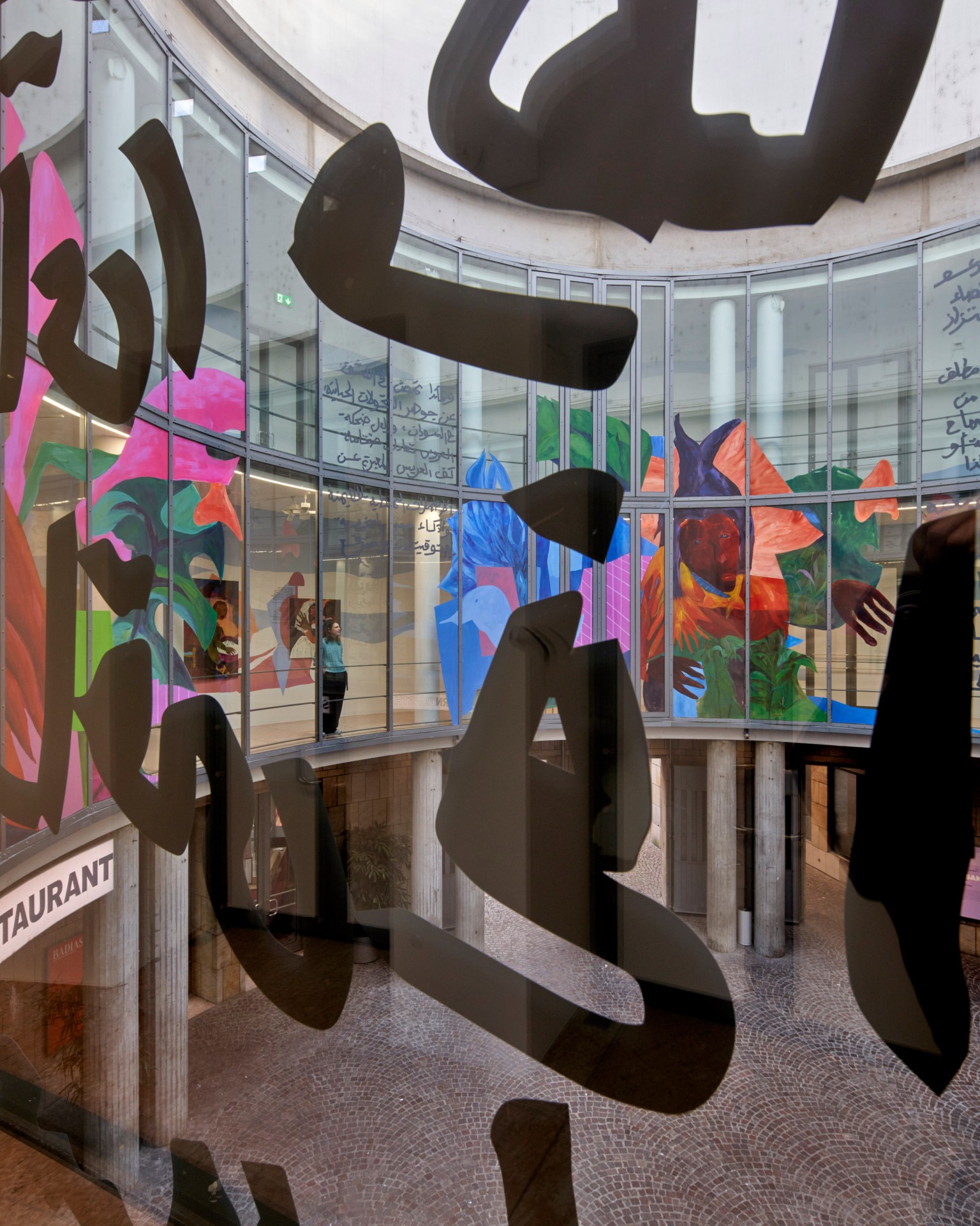 Futuristic interior with colorful murals and glass graphic elements reflecting light.