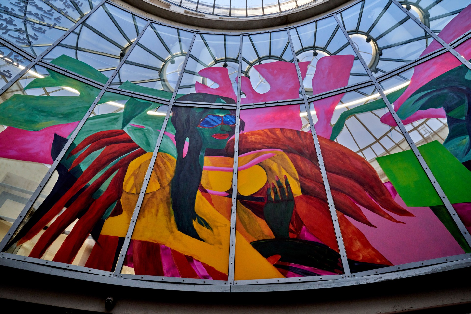 Colorful mural behind glass, featuring a stylized figure with sunglasses and vivid, colorful elements.