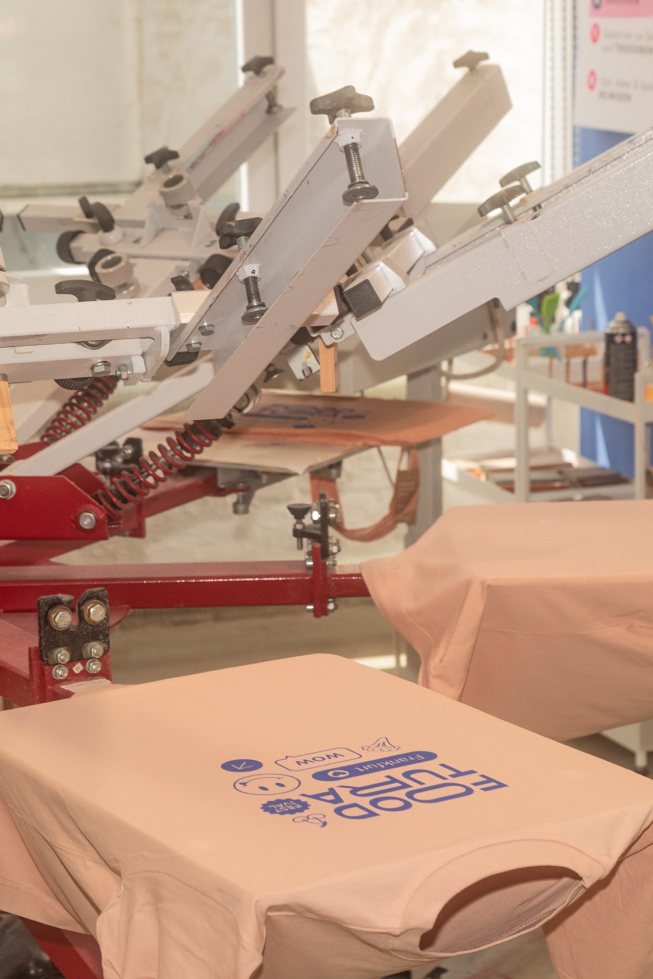Druckmaschine in einem Atelier, die bunte Designs auf T-Shirts anbringt.