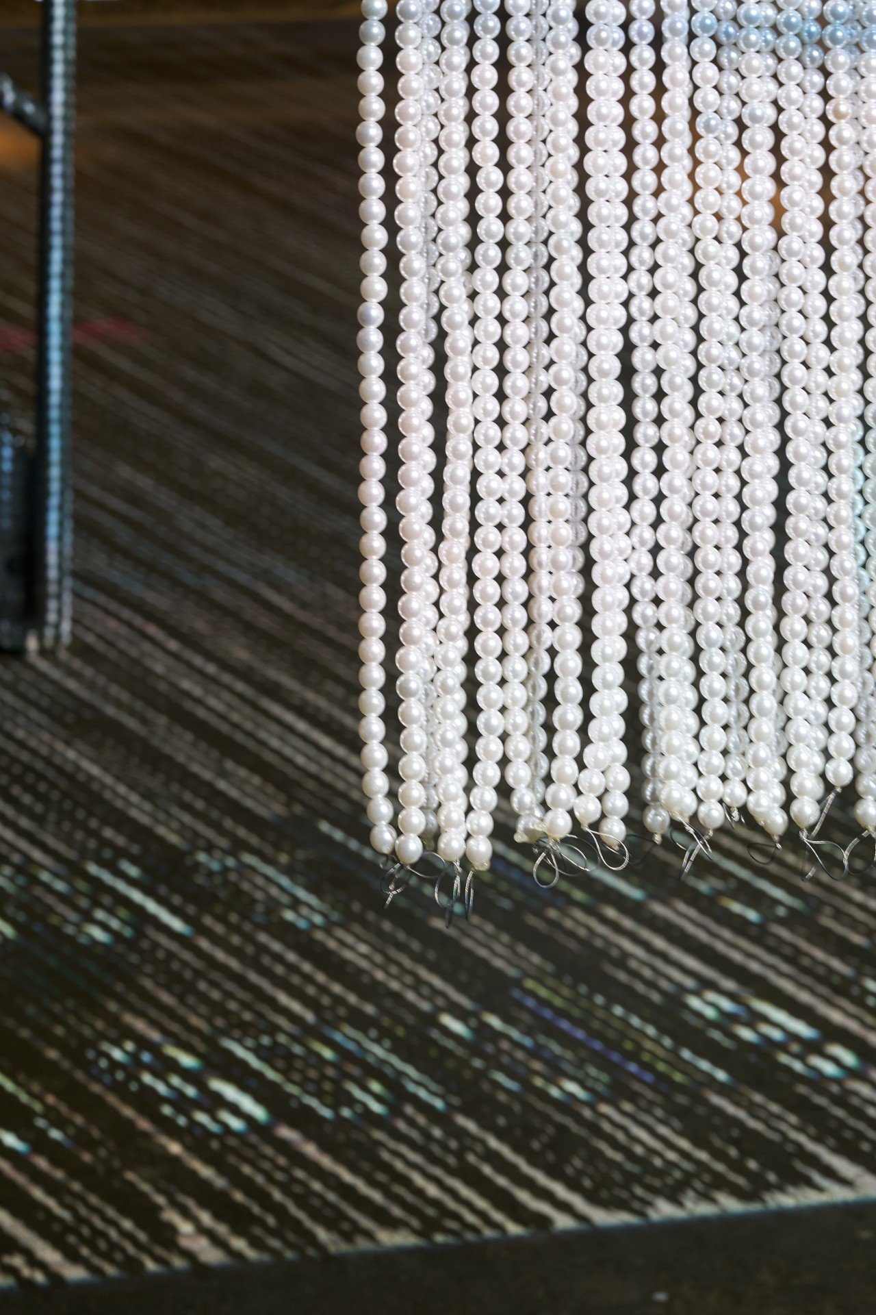 A white bead curtain hangs in front of a patterned floor covering in a modern room.