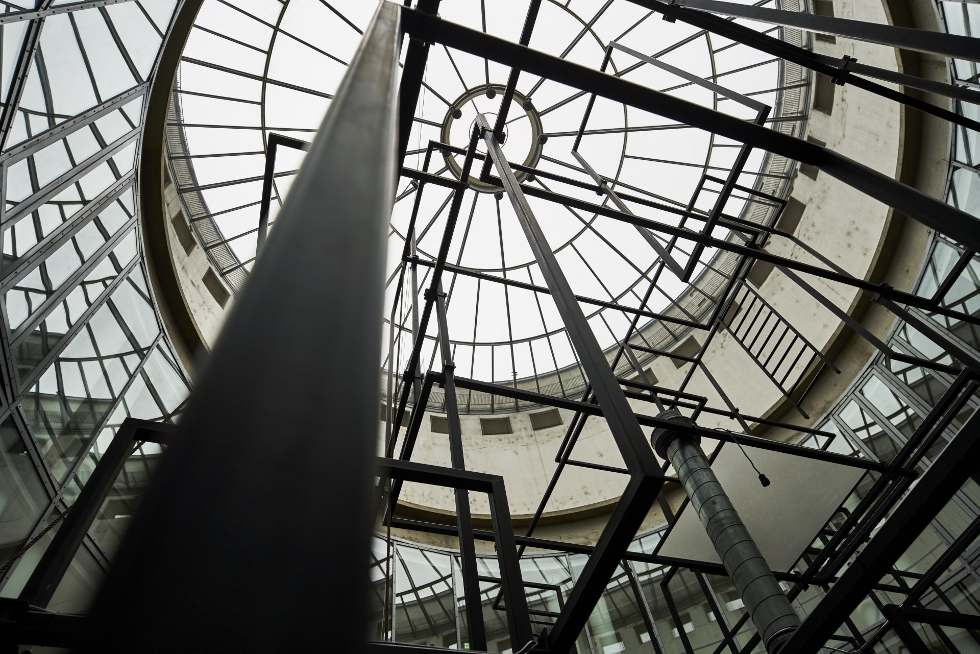 Blick nach oben in ein modernes Gebäude mit klaren Linien, Metallrahmen und großem Glasdach.