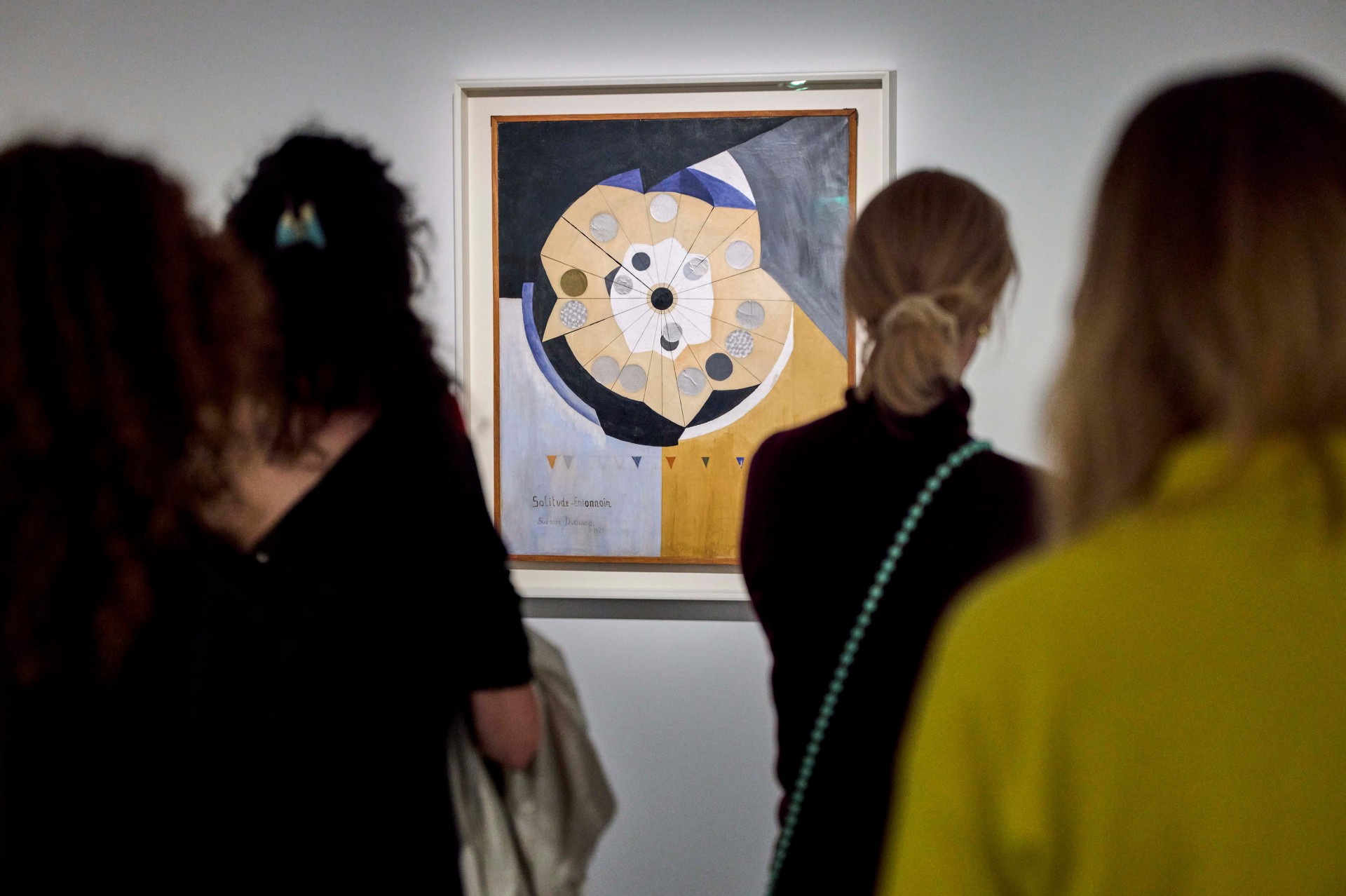 Besucher betrachten ein abstraktes Kunstwerk mit geometrischen Formen in einer Galerie.