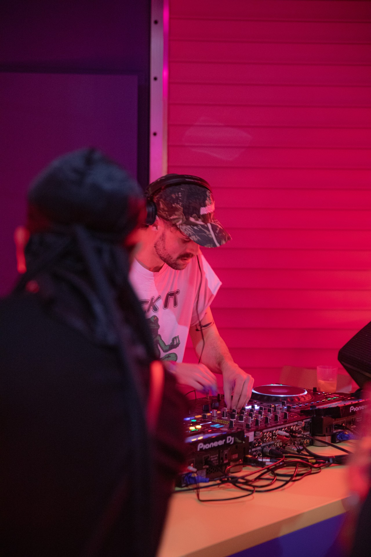 DJ legt in einem strahlend pinken Raum konzentriert an einem Mischpult auf.