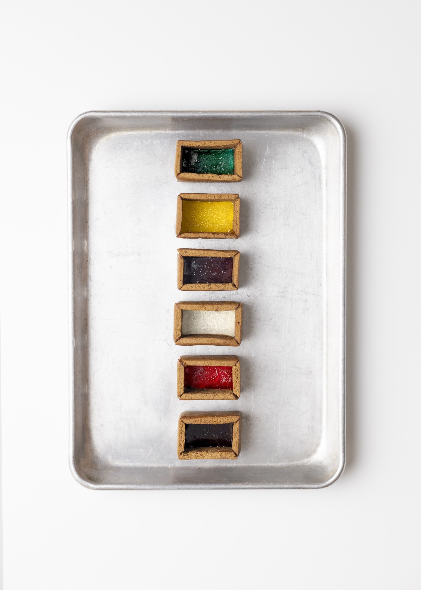 Bunt gefüllte Behälter auf einem Metalltablett, die verschiedene Farben und Texturen präsentieren.