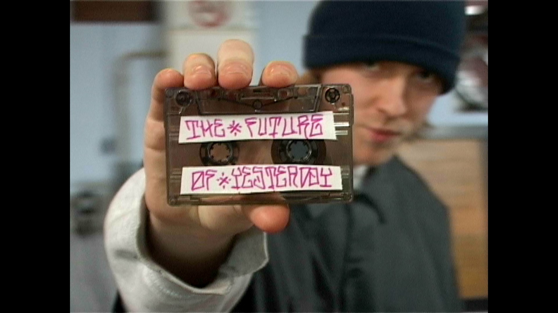 Junger Mann hält eine beschriftete Kassette mit dem Titel "Die Zukunft von Gestern" in der Hand.