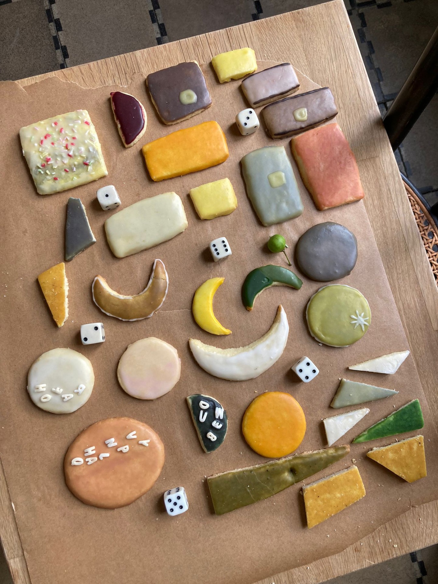 Bunt verzierte Kekse in verschiedenen Formen und Farben, auf braunem Papier arrangiert.