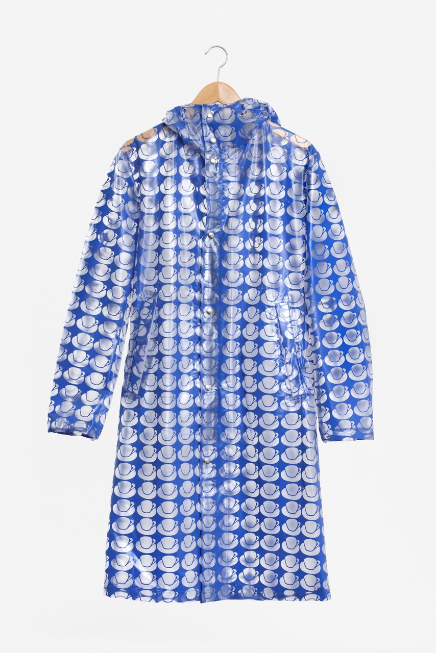 Transparenter blauer Regenmantel mit weißen Hut-Mustern, an einem Holzkleiderbügel aufgehängt.