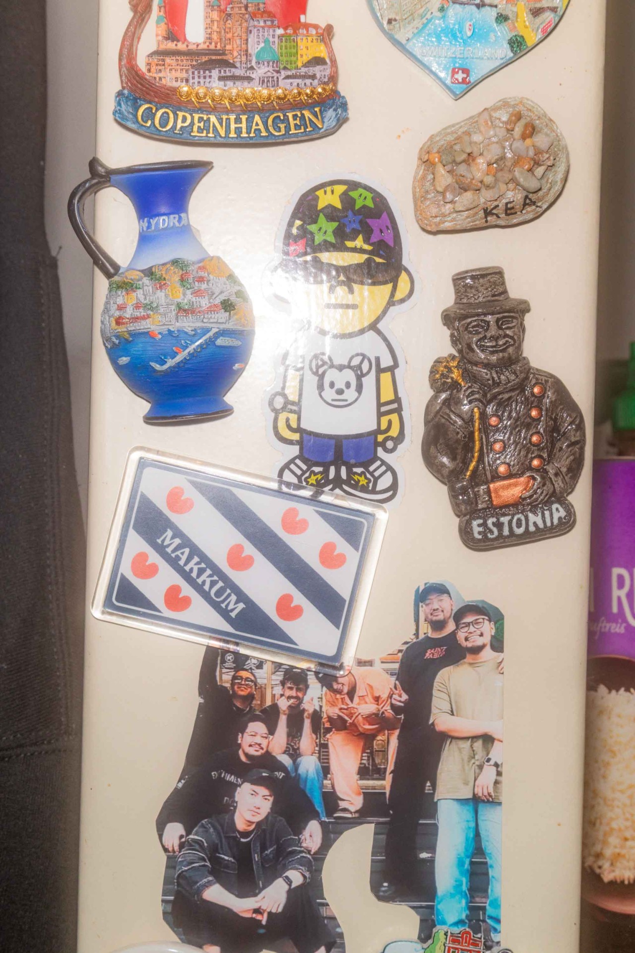 Kühlschrank mit bunten Magneten: Souvenirs, Figuren und ein Gruppenfoto.