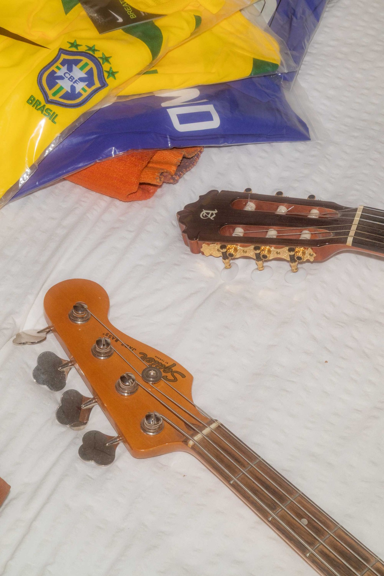 Zwei Musikinstrumente und brasilianische Trikots auf einer Bettdecke.