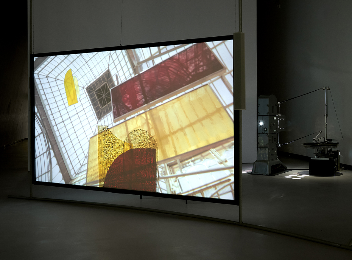 Projektionsfläche mit farbenfrohen Mustern und geometrischen Formen in einem zeitgenössischen Ausstellungsraum.