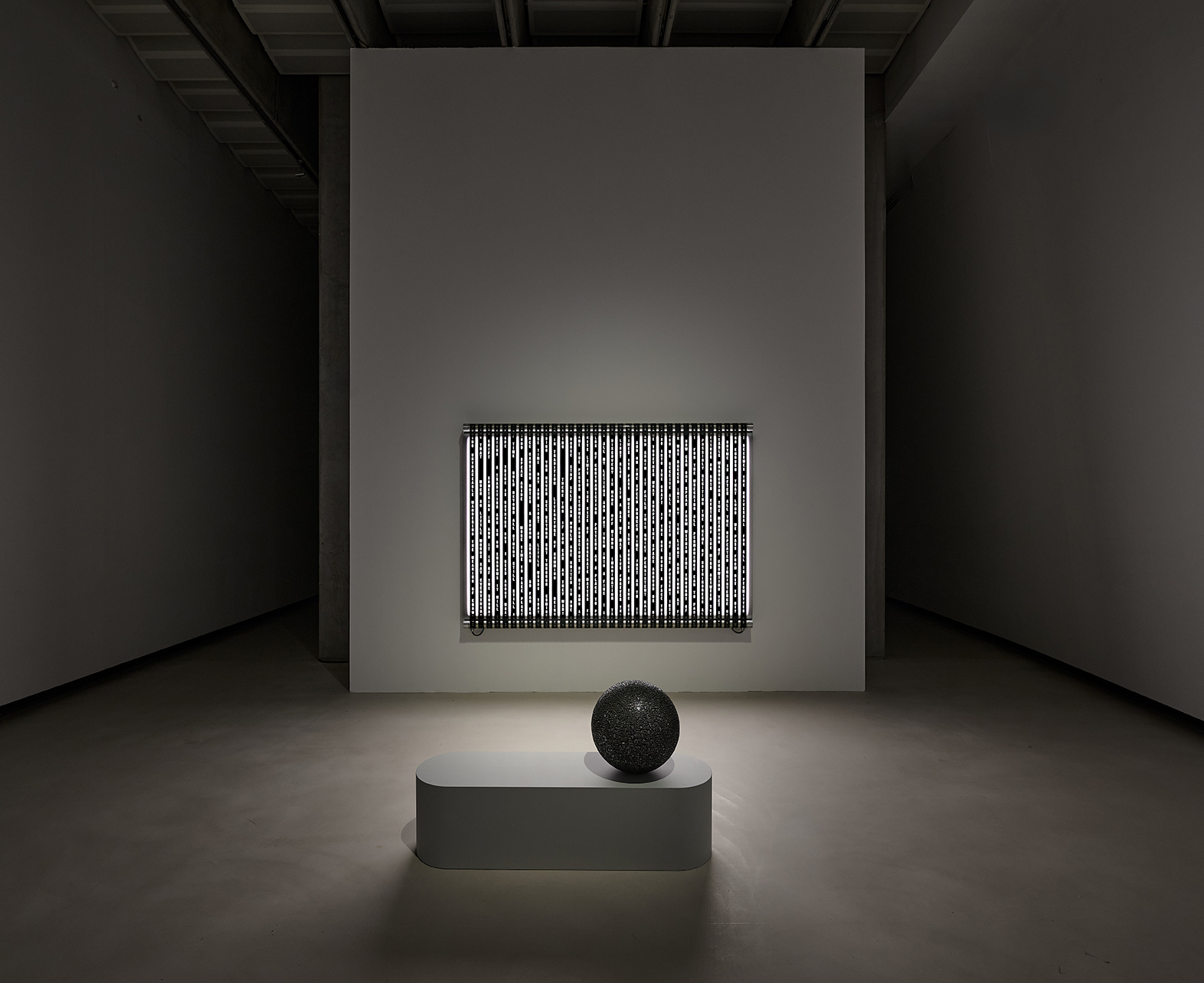 Moderne Galerie mit leuchtendem, gestreiftem Kunstwerk und glänzender Kugel auf minimalistischem, weißem Podest.