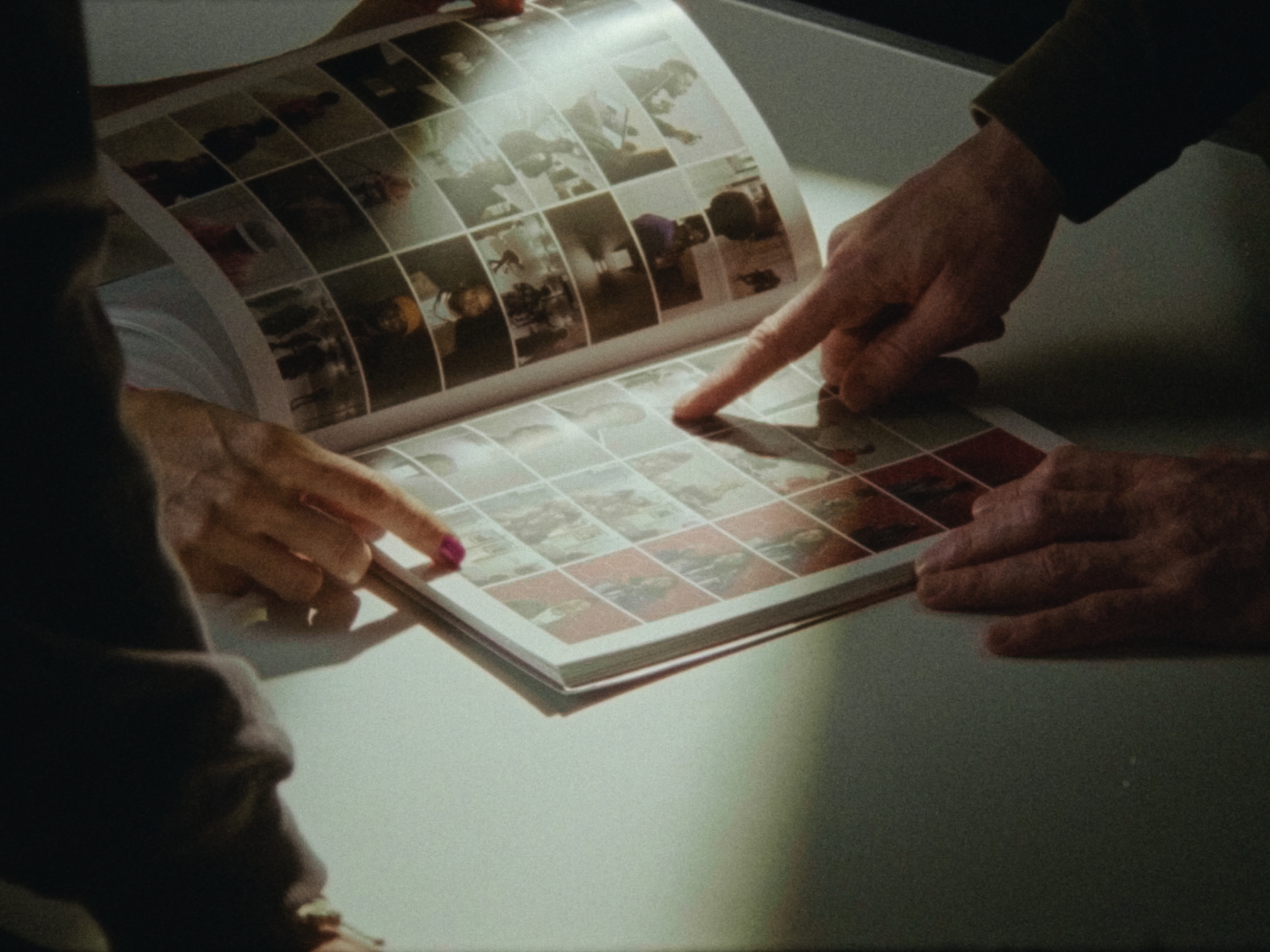 Hände zeigen auf Bilder in einem offenen Buch auf dem Tisch. Gemütliche Atmosphäre.