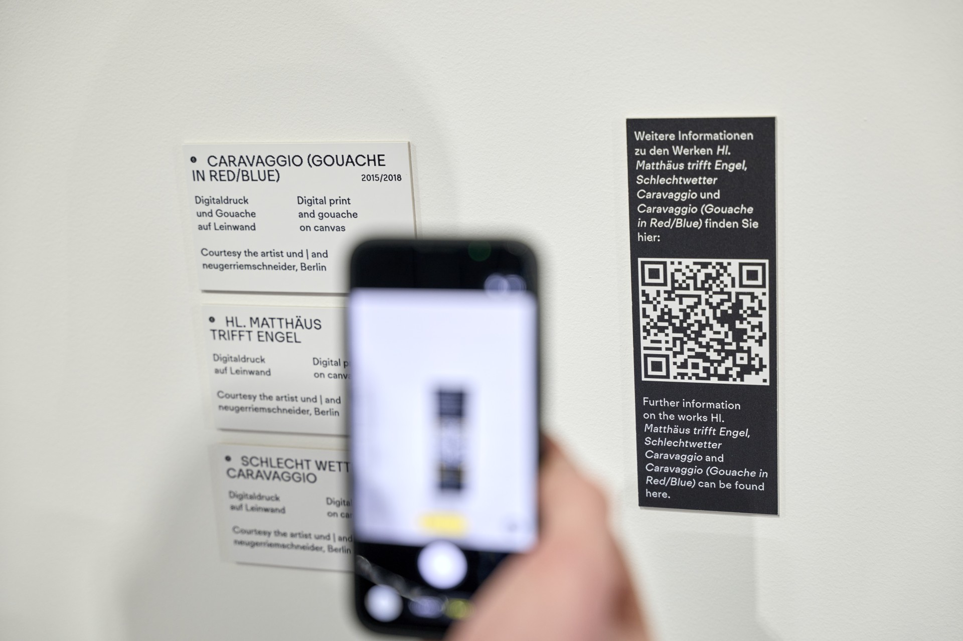 Info-Tafeln zu Caravaggios Kunstwerken mit QR-Code für weitere Infos. Handykamera scannt QR-Code.