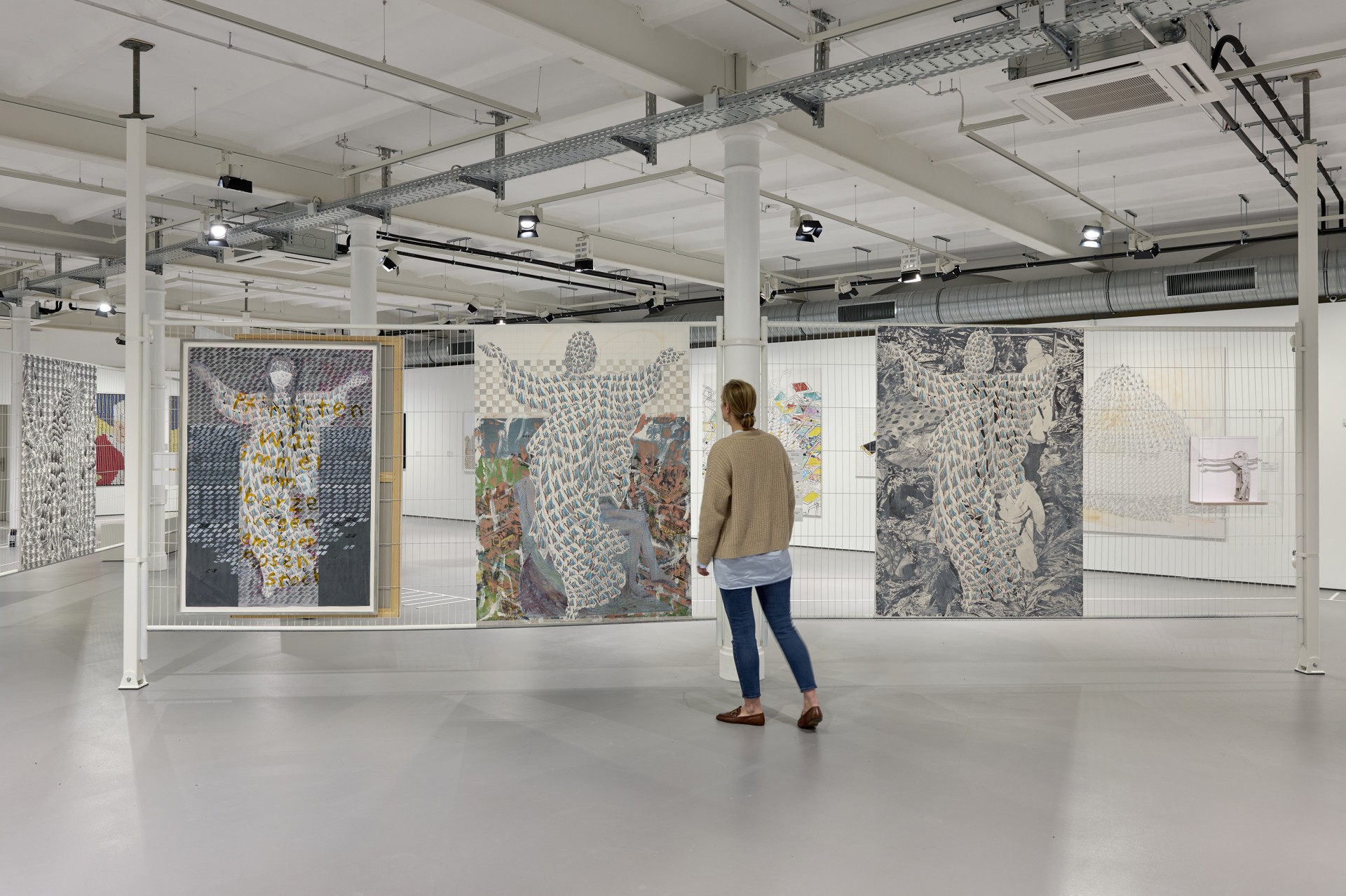 A person is viewing artworks in a modern gallery featuring several displayed images.