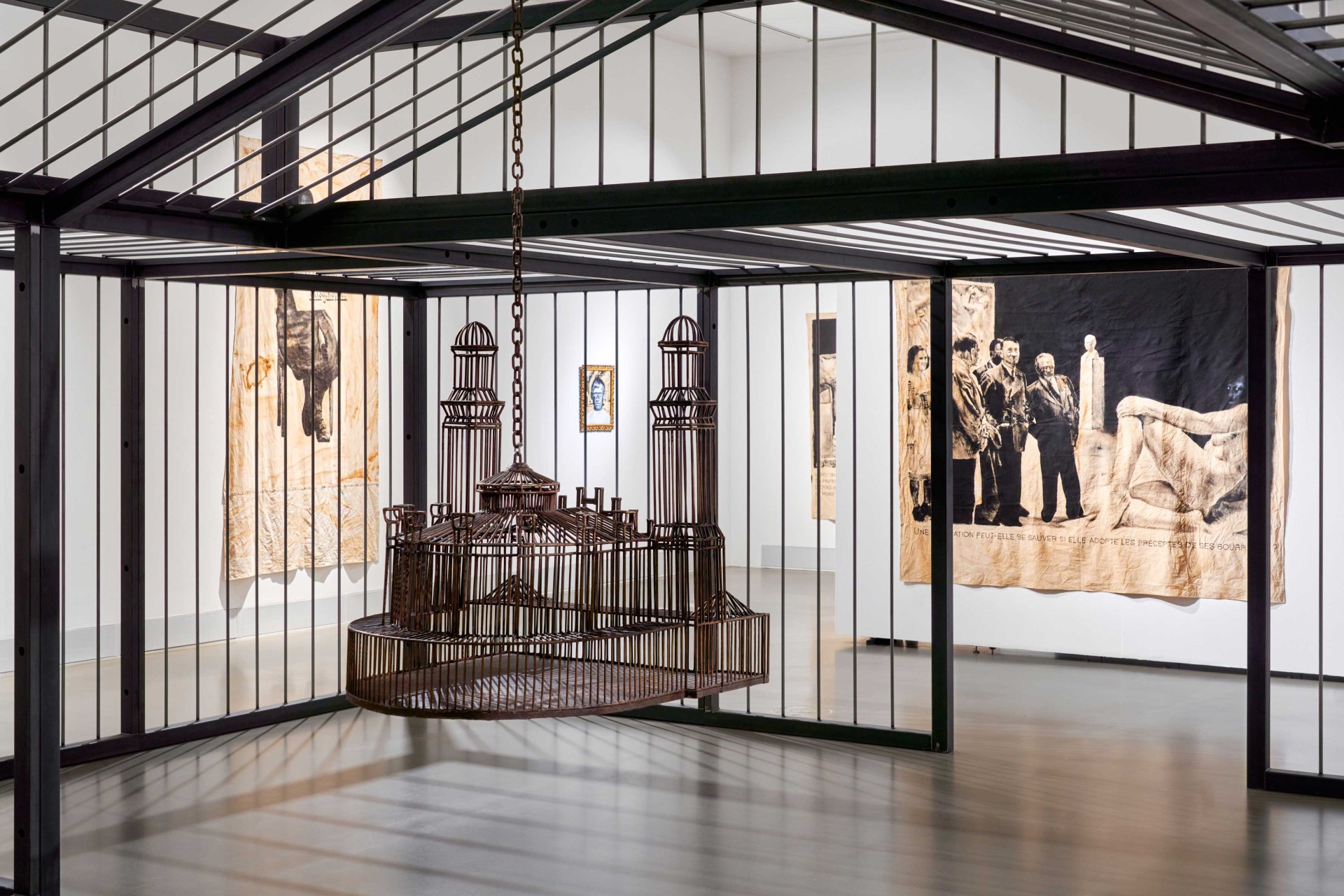 Moderne Galerie mit künstlerischem Gitterobjekt und historischen Wandteppichen im Hintergrund.