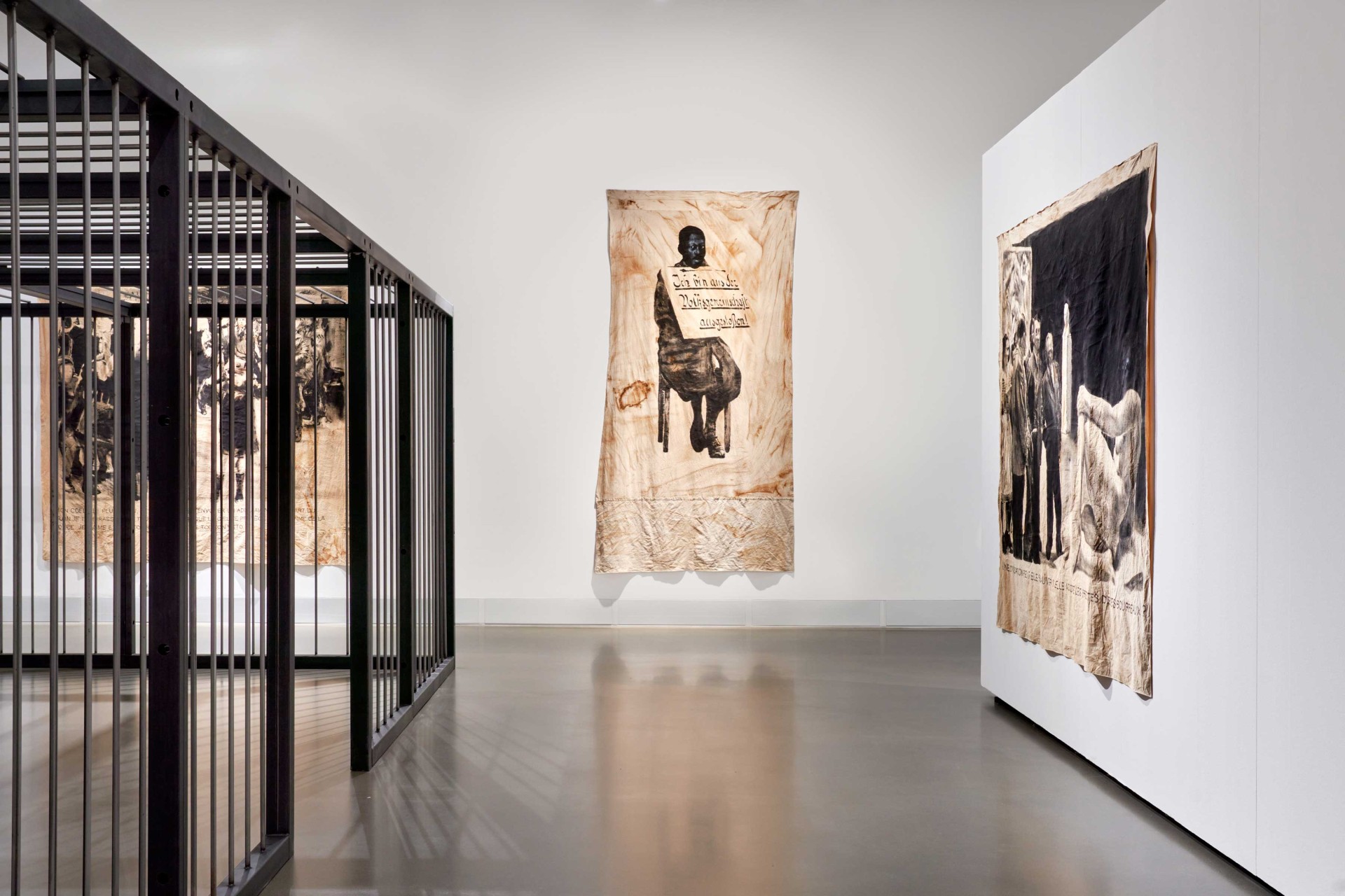 Überblick über eine Kunstinstallation mit großen Wandbildern und einem Metallnetz.