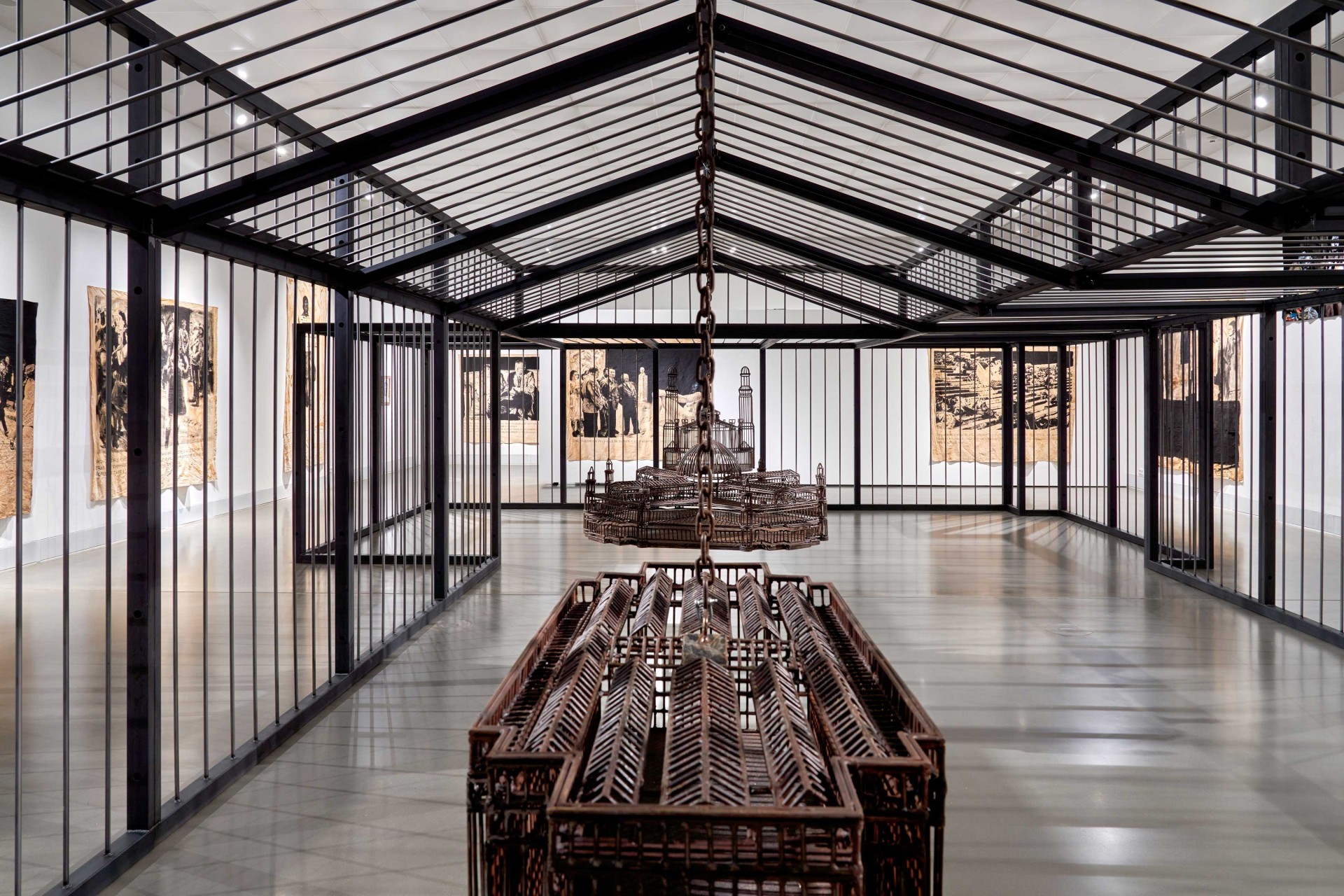 Moderne Kunstausstellung mit Gittern, Hängemöbeln und Wandbildern in klarem, minimalistischen Ambiente.