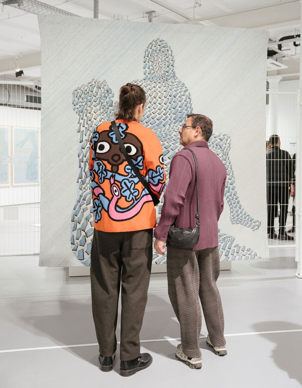 Zwei Personen bewundern ein Kunstwerk in einer Ausstellung, umgeben von modernen architektonischen Elementen.