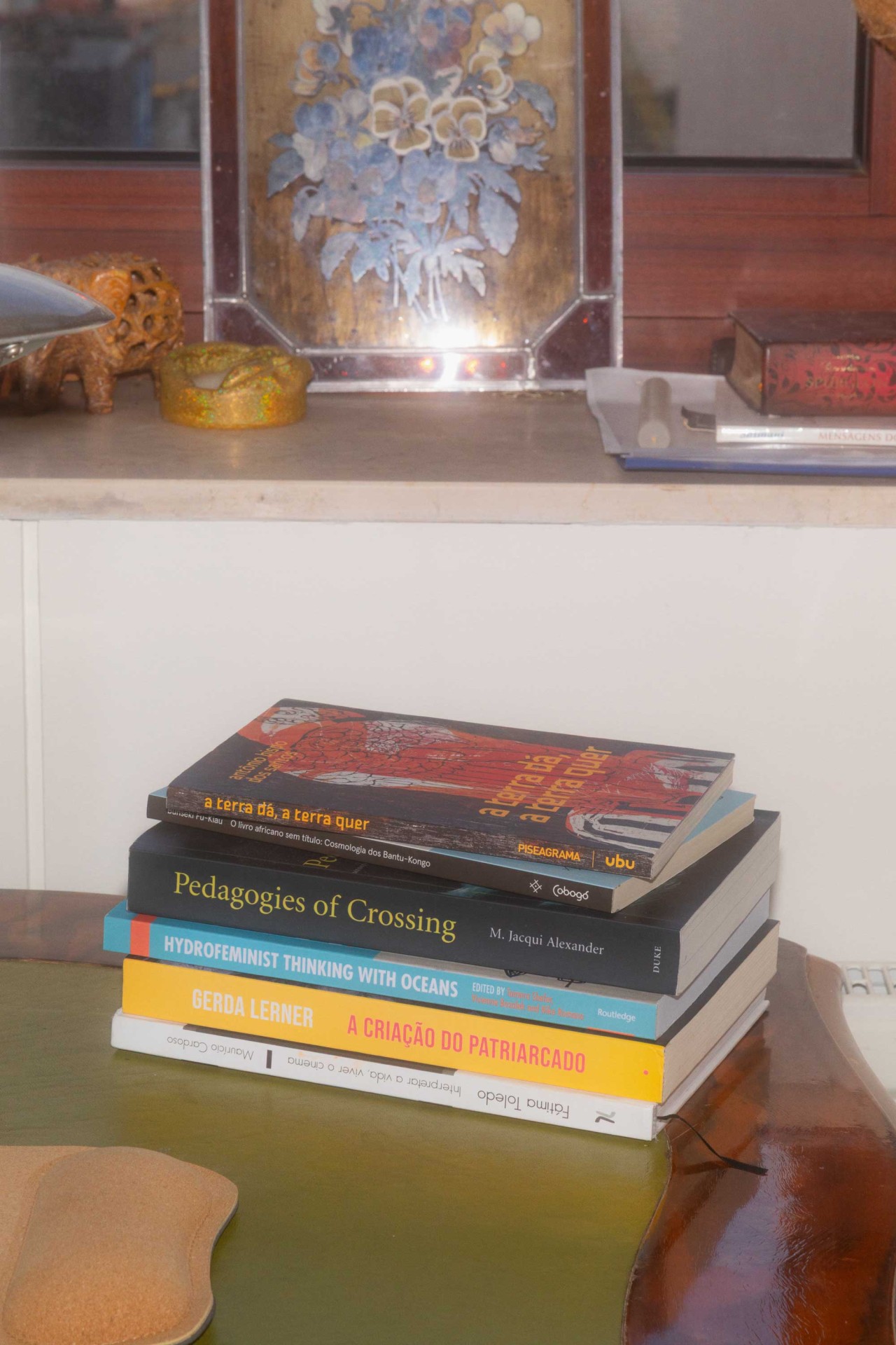 Fünf Bücher auf einem Tisch, daneben eine dekorative Schale und im Hintergrund ein Bild mit Blumenmotiv.