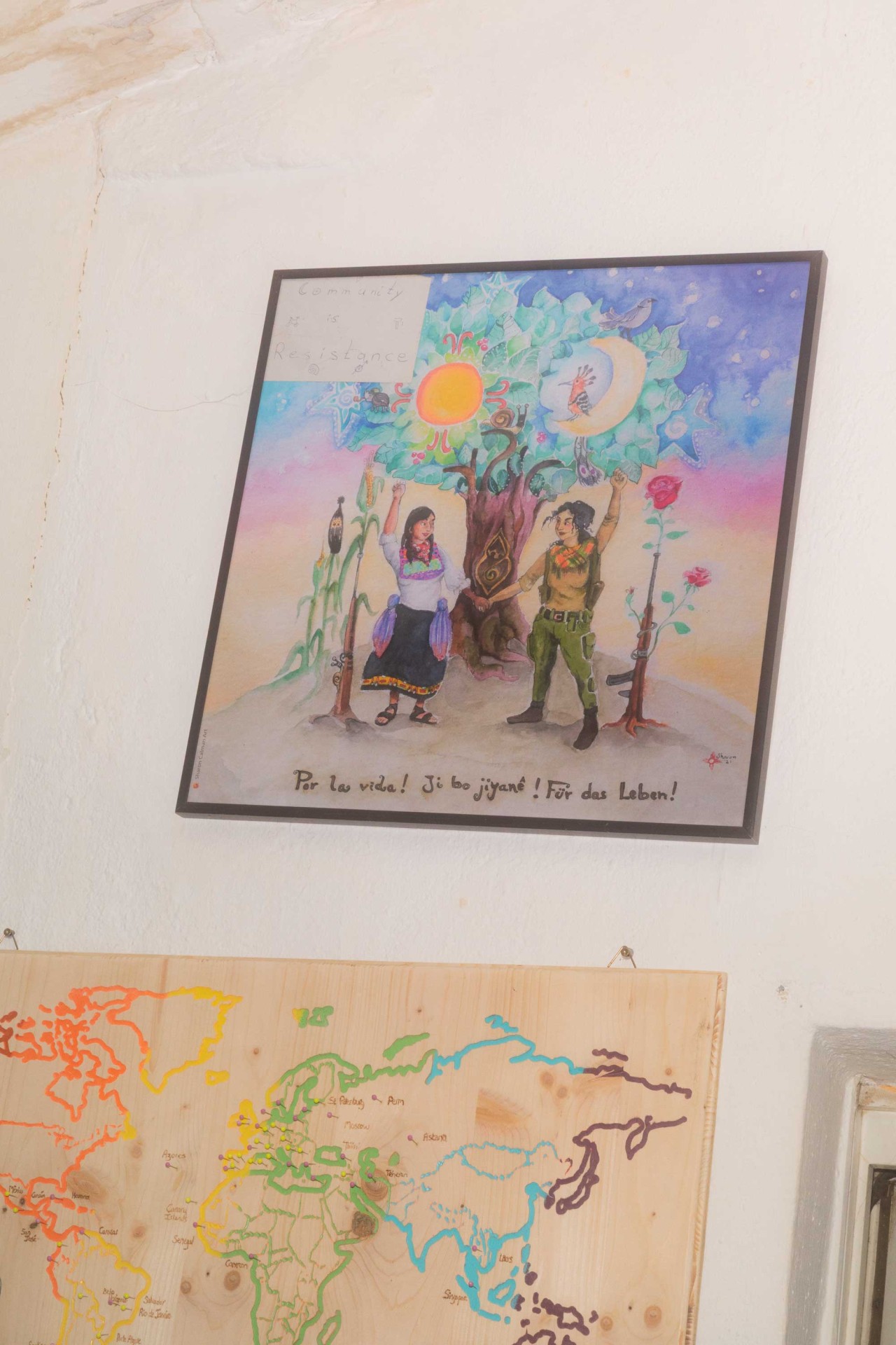 Buntes Kunstwerk mit zwei Figuren, Sonne, Mond und Pflanzen symbolisiert Gemeinschaft und Widerstand.