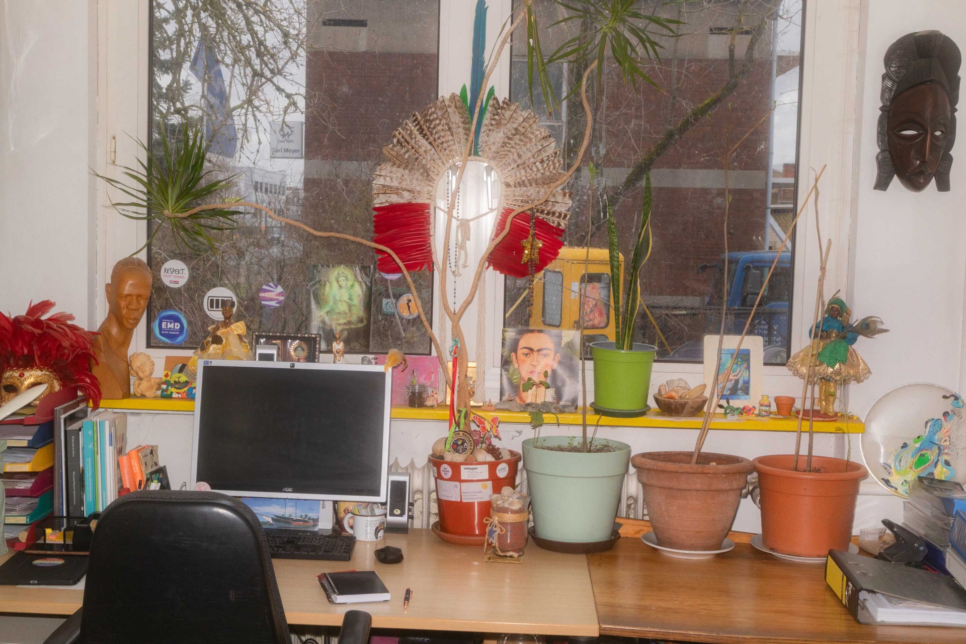 Büroansicht mit Pflanzen, Dekoration, Computer und Fensterblick auf die Straße.