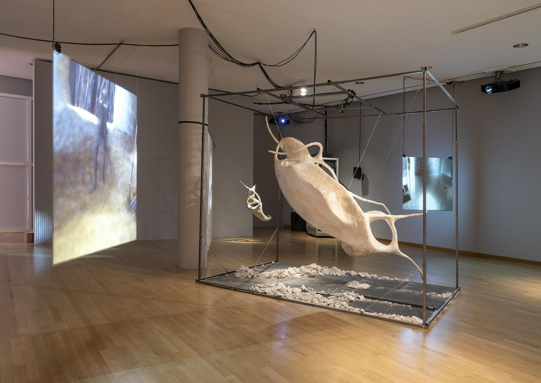 Installation mit skulpturalen Elementen und Projektionen in einem zeitgenössischen Raum.