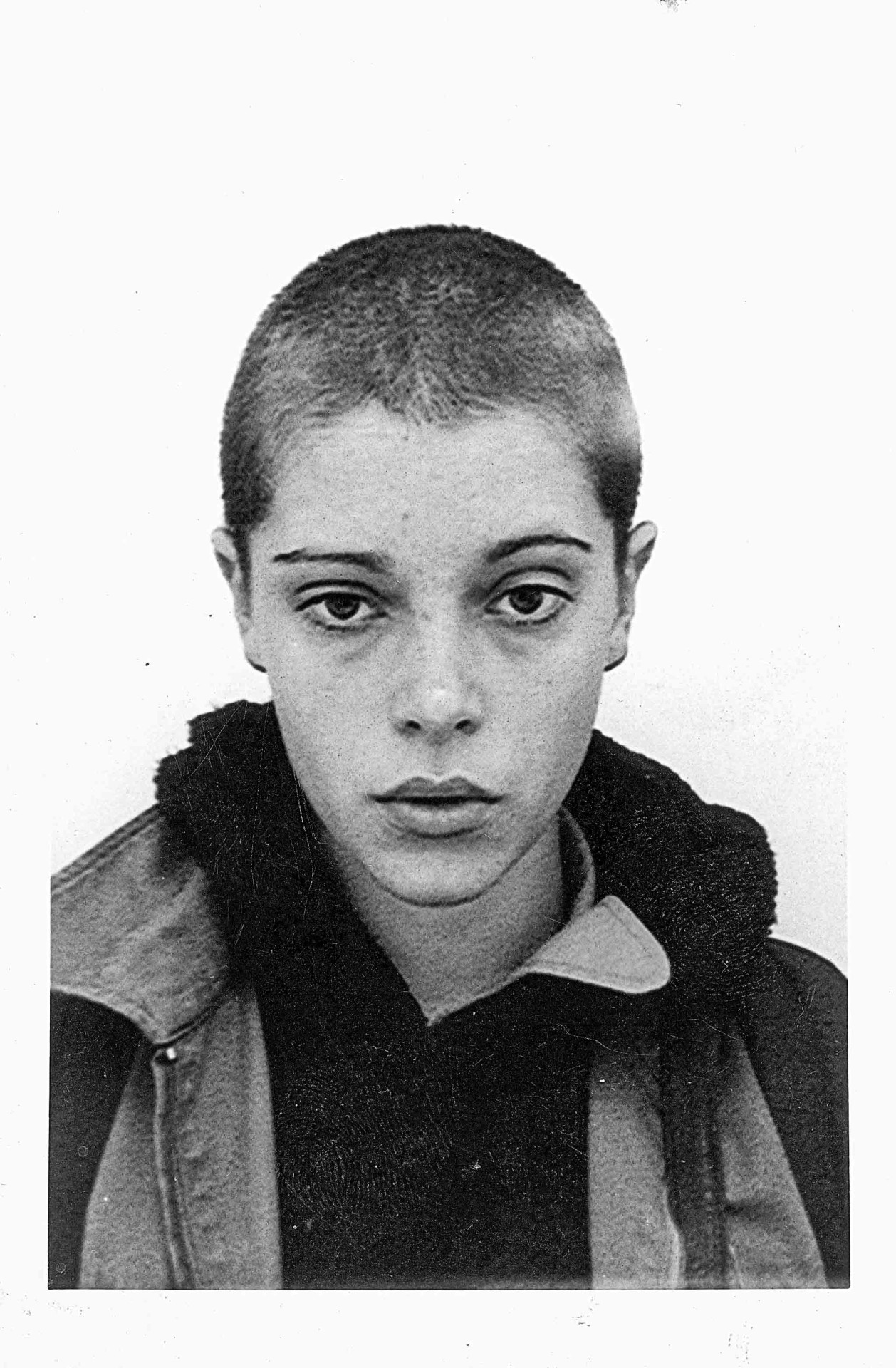 Schwarz-Weiß-Porträt eines jungen Menschen mit kurzen Haaren und ernstem Gesichtsausdruck in neutraler Pose.