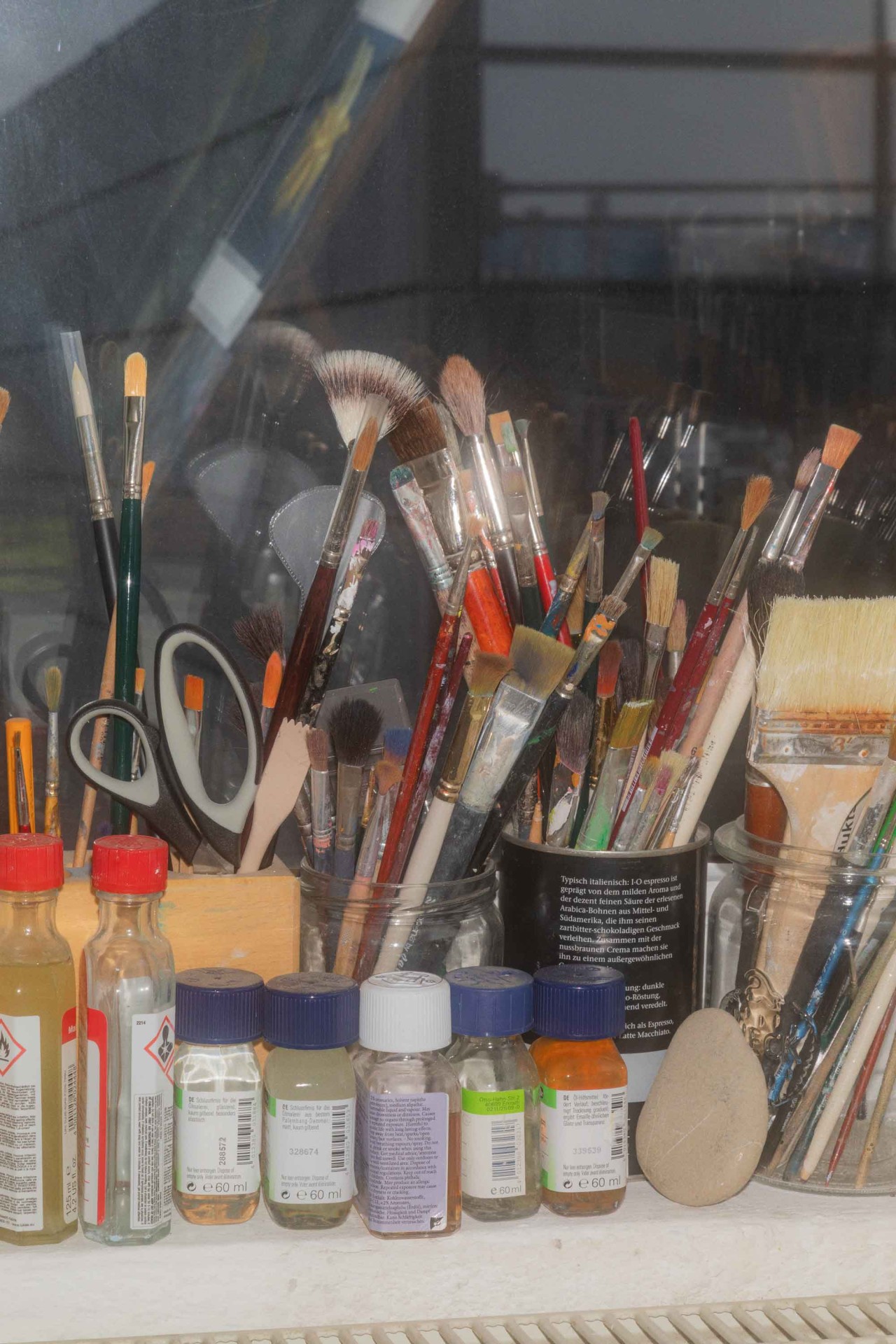 Eine Ansammlung von Malutensilien: Pinsel, Scheren und Farbflaschen liegen auf einem Tisch.