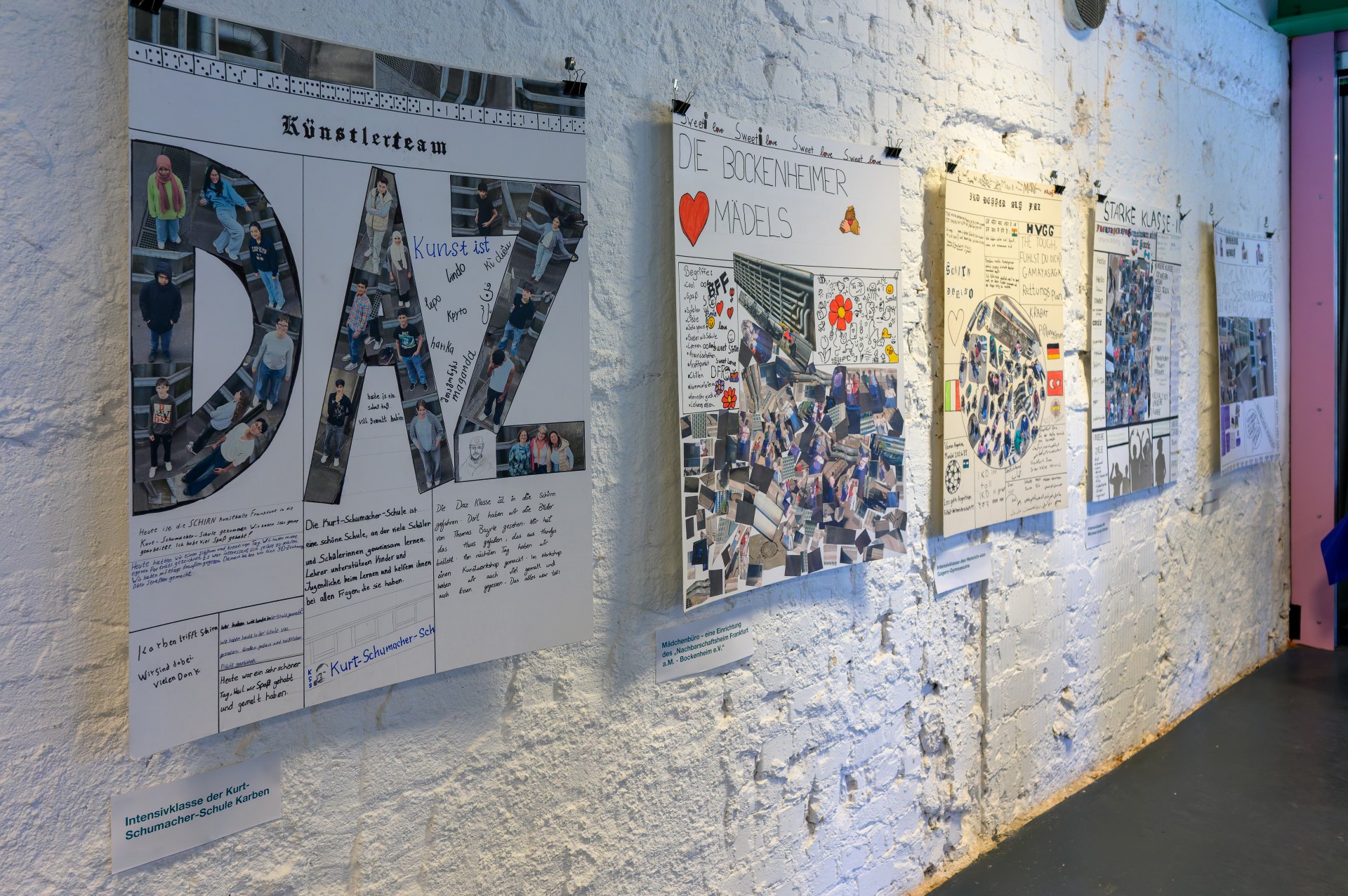 Kunstwerke von Schülern der Kurt-Schumacher-Schule, ausgestellt an einer Wand mit Collagen und Informationen.