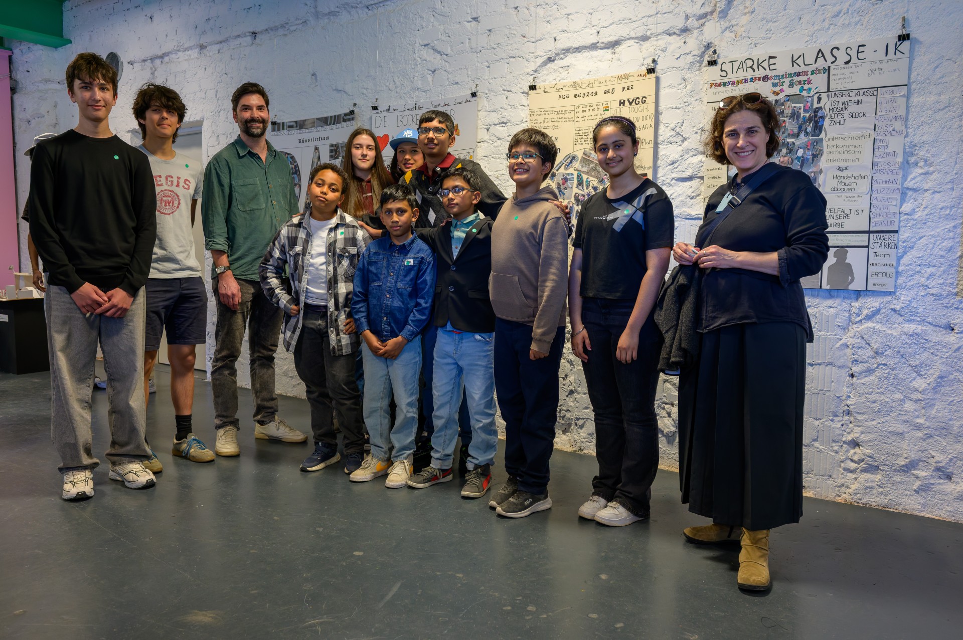 Gruppenfoto von Jugendlichen und Betreuenden in einem Raum mit Kunstwerken an der Wand.