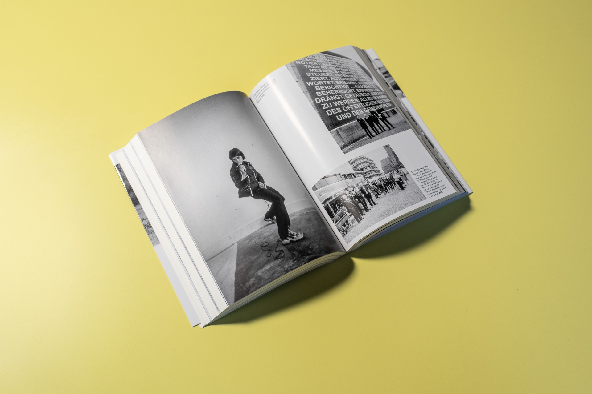 Offenes Buch auf gelbem Hintergrund mit Schwarz-Weiß-Fotos und Text auf den Seiten.