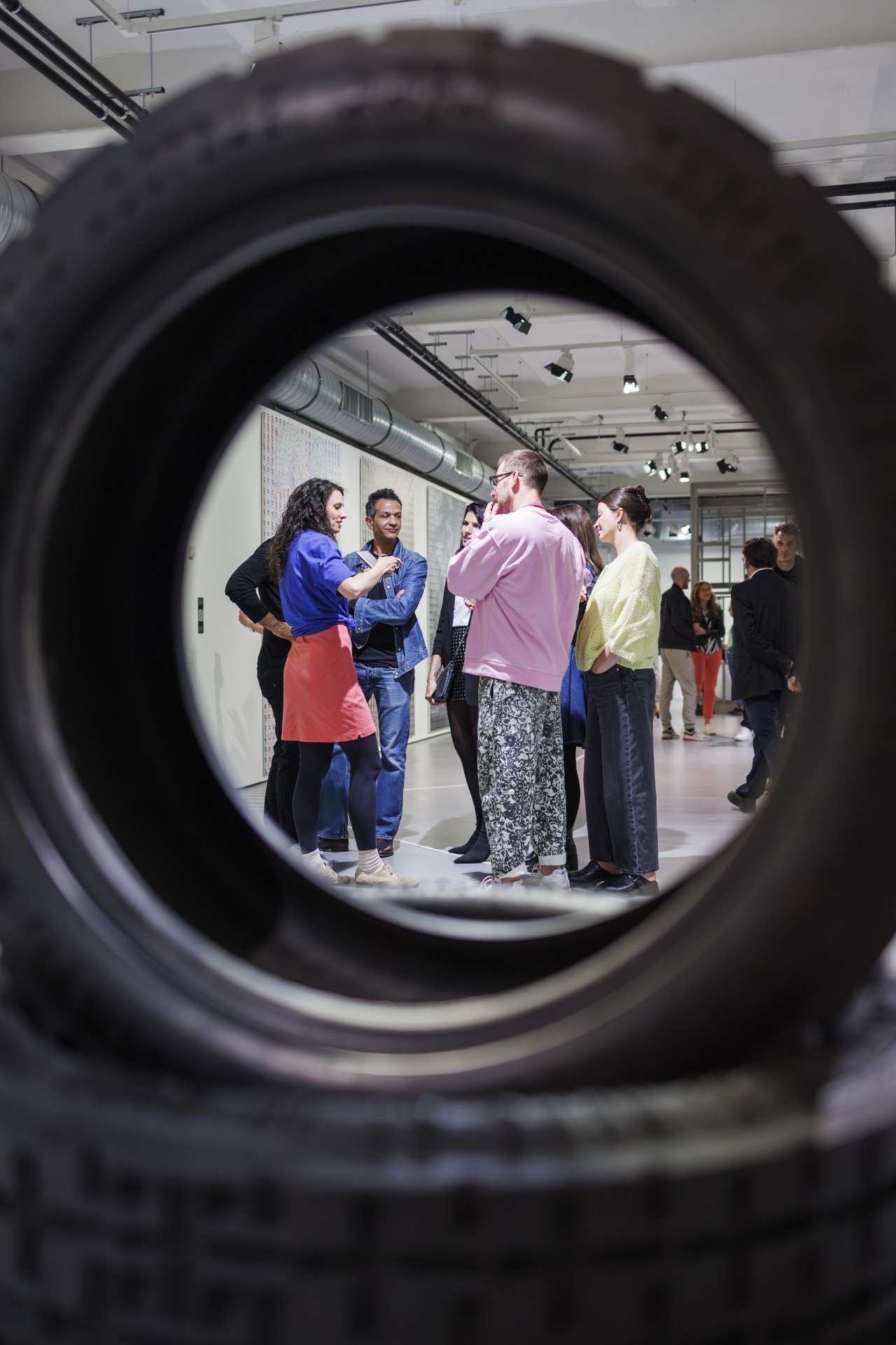 Gesprächsgruppe im Kunstraum, sichtbar durch einen Reifen, kreative Atmosphäre und vielfältige Outfits.