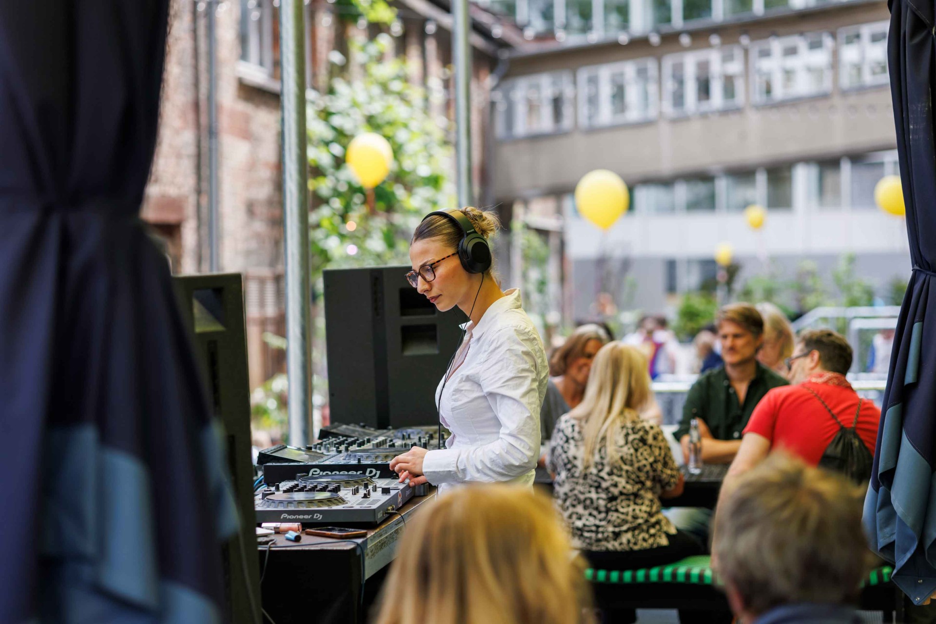 DJ plays music at an outdoor event while guests sit relaxed and celebrate.