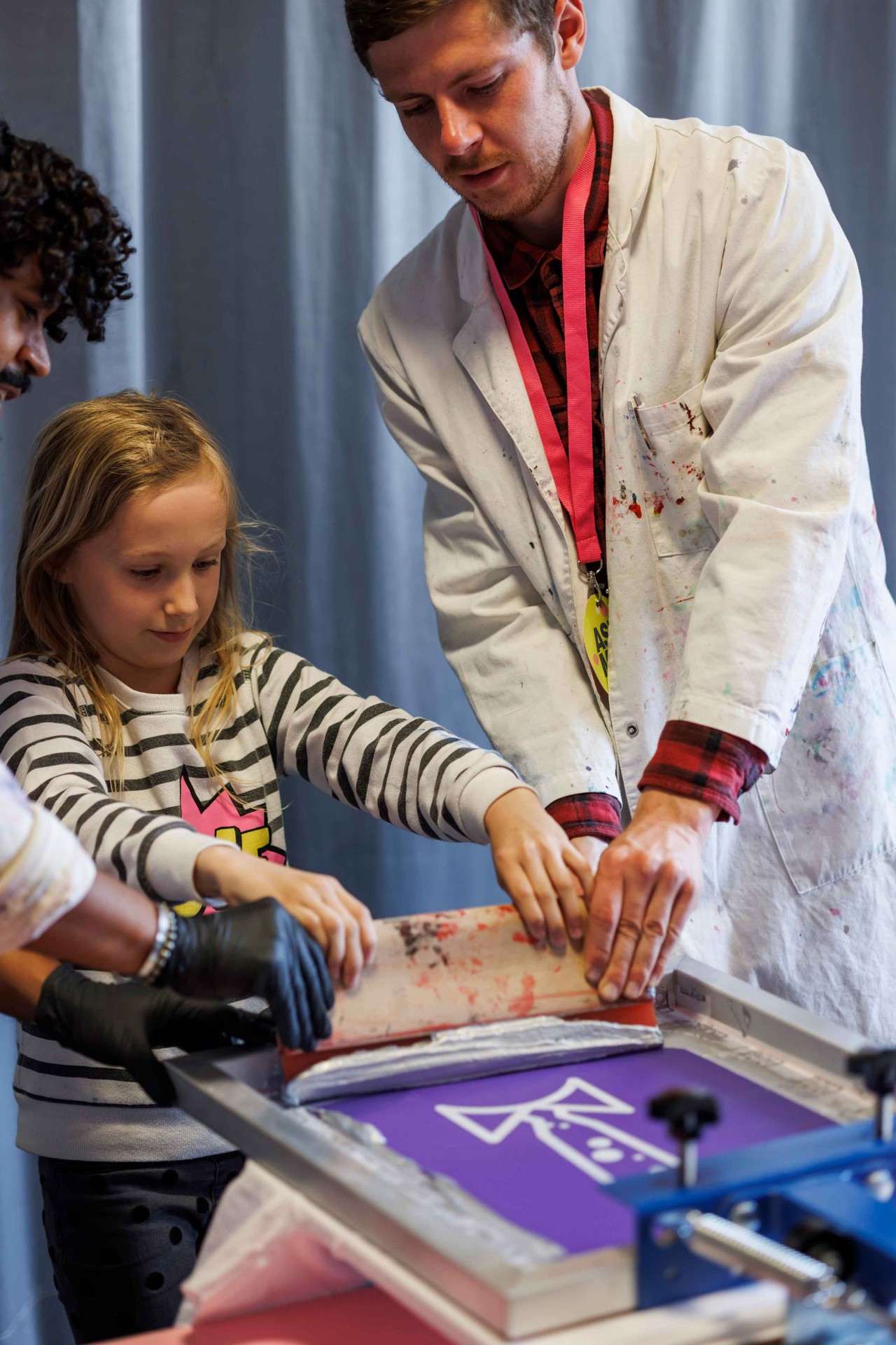 Creative printing session: A teacher and a child work together on a screen printing machine.